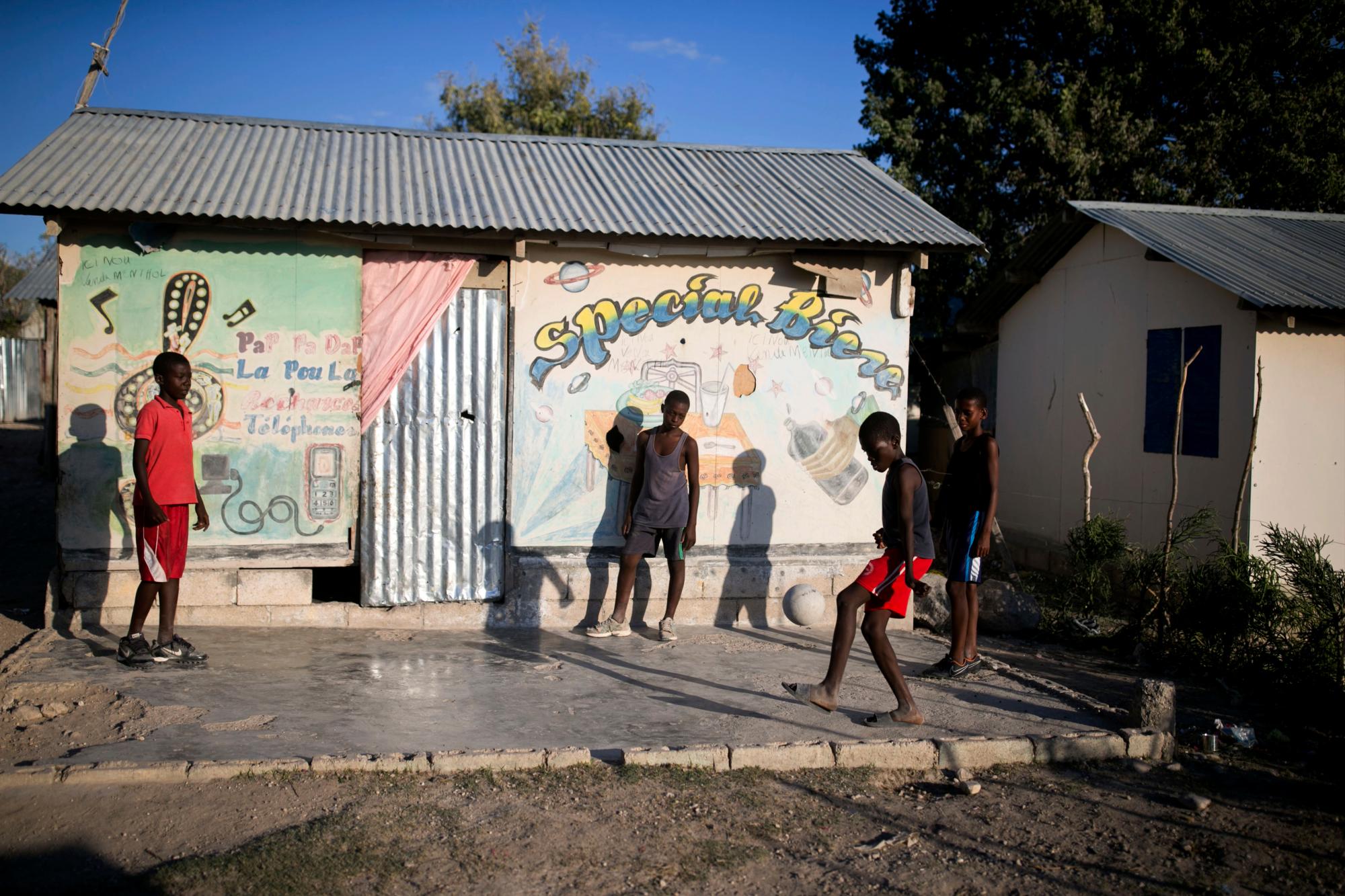 En esta foto del 7 de enero de 2020, los niños juegan fútbol frente a un restaurante en Canaan, un distrito en Croix des Bouquets, Haití creado para las personas que perdieron sus hogares en el terremoto hace 10 años. El terremoto mató a cientos de miles y dejó a más de un millón de personas sin hogar, mientras que la cifra final de muertes sigue siendo debatida. 