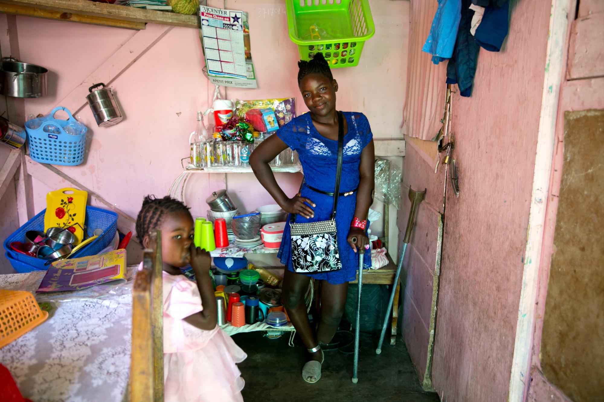 En esta foto del 5 de enero de 2020, apoyada en su muleta, Rose-Berline Thomas, cuyo pie fue aplastado durante un terremoto cuando tenía 2 años, posa para una foto mientras se apoya en un bastón y sus otras piernas arqueadas , junto a su hermana Ruth Sterline en su hogar en Canaan, un distrito en Croix des Bouquets, Haití, creado para las personas que perdieron sus hogares en el terremoto hace 10 años. A los 12 años, dirige la casa mientras su madre trabaja vendiendo artículos para el hogar en la calle. 