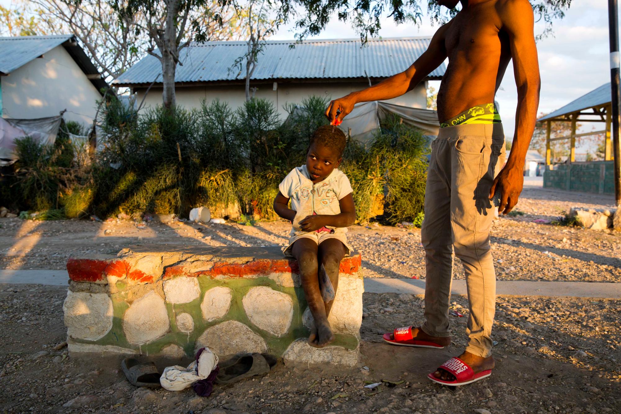 En esta foto del 7 de enero de 2020, Ruth Sterline Thomas se corta el cabello de su prima en Canaan, un distrito en Croix des Bouquets, Haití, creada para las personas que perdieron sus hogares en el terremoto hace 10 años. Antes de que naciera Ruth, un terremoto masivo devastó Haití el 12 de enero de 2010, derrumbando la antigua casa de su familia sobre sus padres y hermanos. La familia sobrevivió y se mudó a este asentamiento, que se ha convertido en el barrio marginal más grande del Caribe. 
