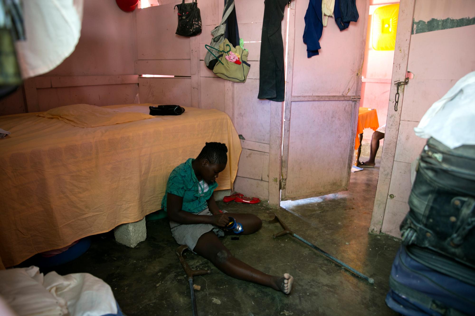 En esta foto del 3 de enero de 2020, Rose-Berline Thomas arregla una lámpara en su habitación en Canaan, un distrito en Croix des Bouquets, Haití, creado para las personas que perdieron sus hogares en el terremoto hace 10 años. Rose-Berline tenía 2 años cuando el terremoto derrumbó la casa de su familia encima de ella, aplastándole el pie, y como sus muletas son demasiado pequeñas, se mueve de una habitación a otra de rodillas. 