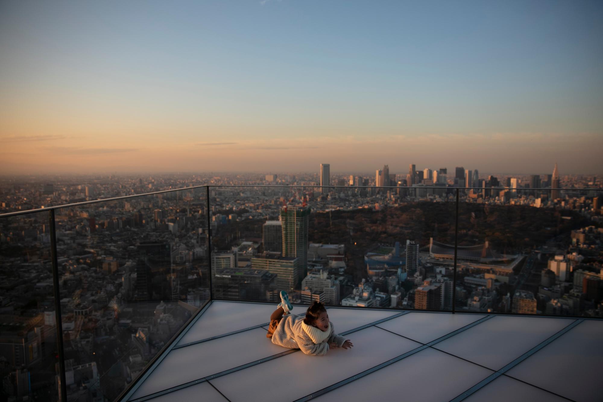 Una niña sonríe mientras posa para fotos en el borde de la plataforma de observación Shibuya Sky con vista al distrito Shibuya de Tokio el lunes 20 de enero de 2020 en Tokio. Ubicado en la azotea de Shibuya Scramble Square, un rascacielos de 47 pisos, el observatorio es la plataforma de observación al aire libre más nueva de Tokio, con vistas al famoso cruce de Shibuya. 
