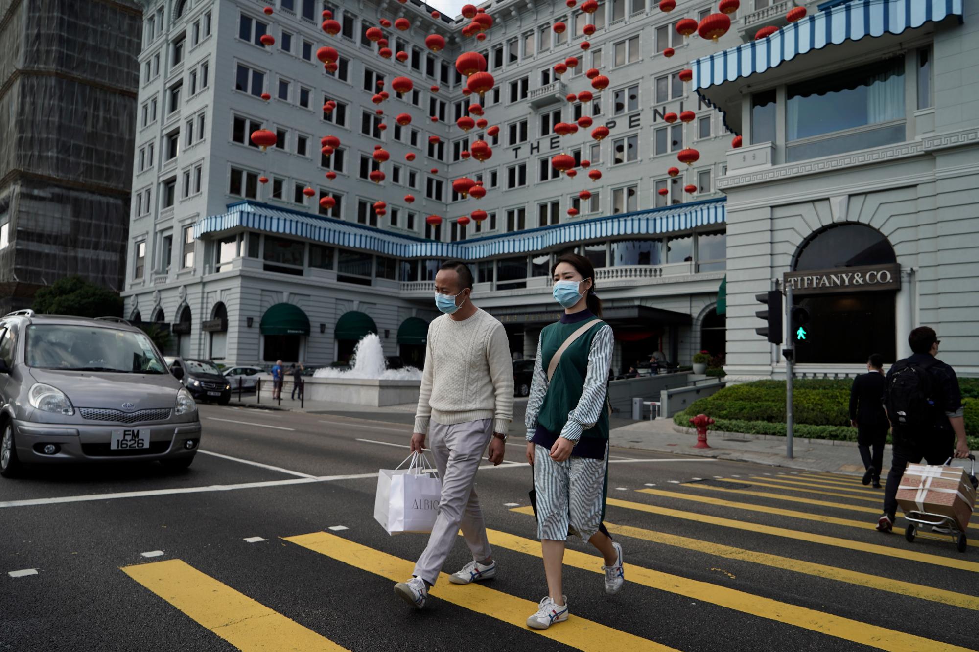 Los turistas usan máscaras faciales protectoras mientras cruzan la calle en Hong Kong, el jueves 23 de enero de 2020. China cerró el jueves una ciudad de más de 11 millones de personas, deteniendo el transporte y advirtiendo contra las reuniones públicas, para tratar de detener la propagación de un nuevo virus mortal que ha enfermado a cientos y se ha extendido a otras ciudades y países en la carrera de viajes del Año Nuevo Lunar. 