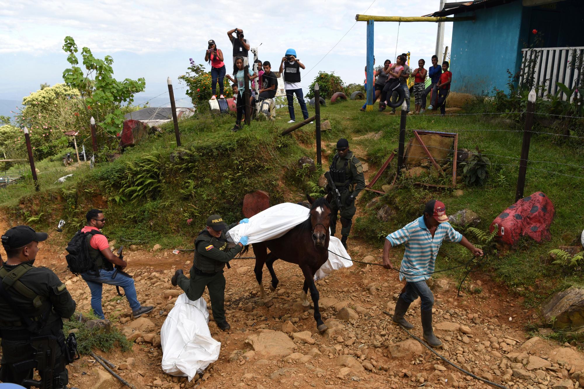 En esta imagen, tomada el 17 de enero de 2020, un agente de la policía ayuda a trasladar el cadáver de uno de los al menos cinco fallecidos en una escaramuza entre grupos ilegales armados, en Jamundi, Colombia. Según las autoridades, rebeldes de las antiguas Fuerzas Armadas Revolucionarias de Colombia (FARC) operan en la zona y podrían haber estado implicados. (AP Foto/Christian Escobar Mora)