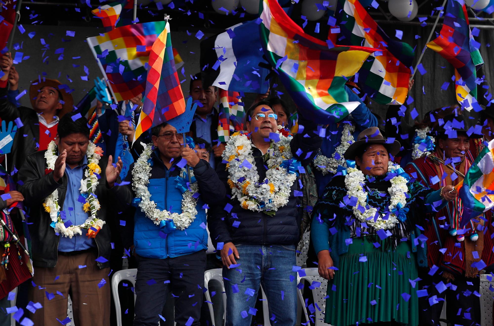 En esta imagen, tomada el 8 de febrero de 2020, una lluvia de confeti cae sobre Luis Arce (centro), candidato a la presidencia de Bolivia del Movimiento al Socialismo (MAS), y sobre su compañero de boleta, David Choquehuanca (segundo por la izquierda), durante su primer acto de campaña, en El Alto, Bolivia. Arce fue nombrado por el exiliado expresidente Evo Morales como candidato de su partido para las presidenciales que se celebrarán el próximo 3 de mayo. (AP Foto/Juan Karita)