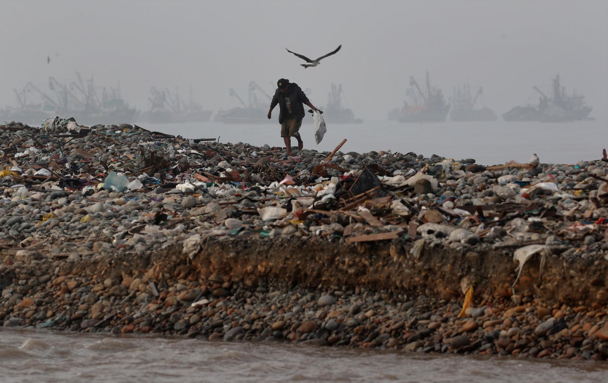 En esta imagen, tomada el 7 de febrero de 2020, un hombre camina sobre un manto de basura acumulada entre la orilla del Río Chillón (abajo), y el Océano Pacífico en busca de cosas que pueda reutilizar o vender, en Callao, Perú. El Río Chillón, que comienza en los Andes y desemboca en el Océano Pacífico y es una importante fuente de agua para la capital del país, está lleno de contaminantes. (AP Foto/Martín Mejía)