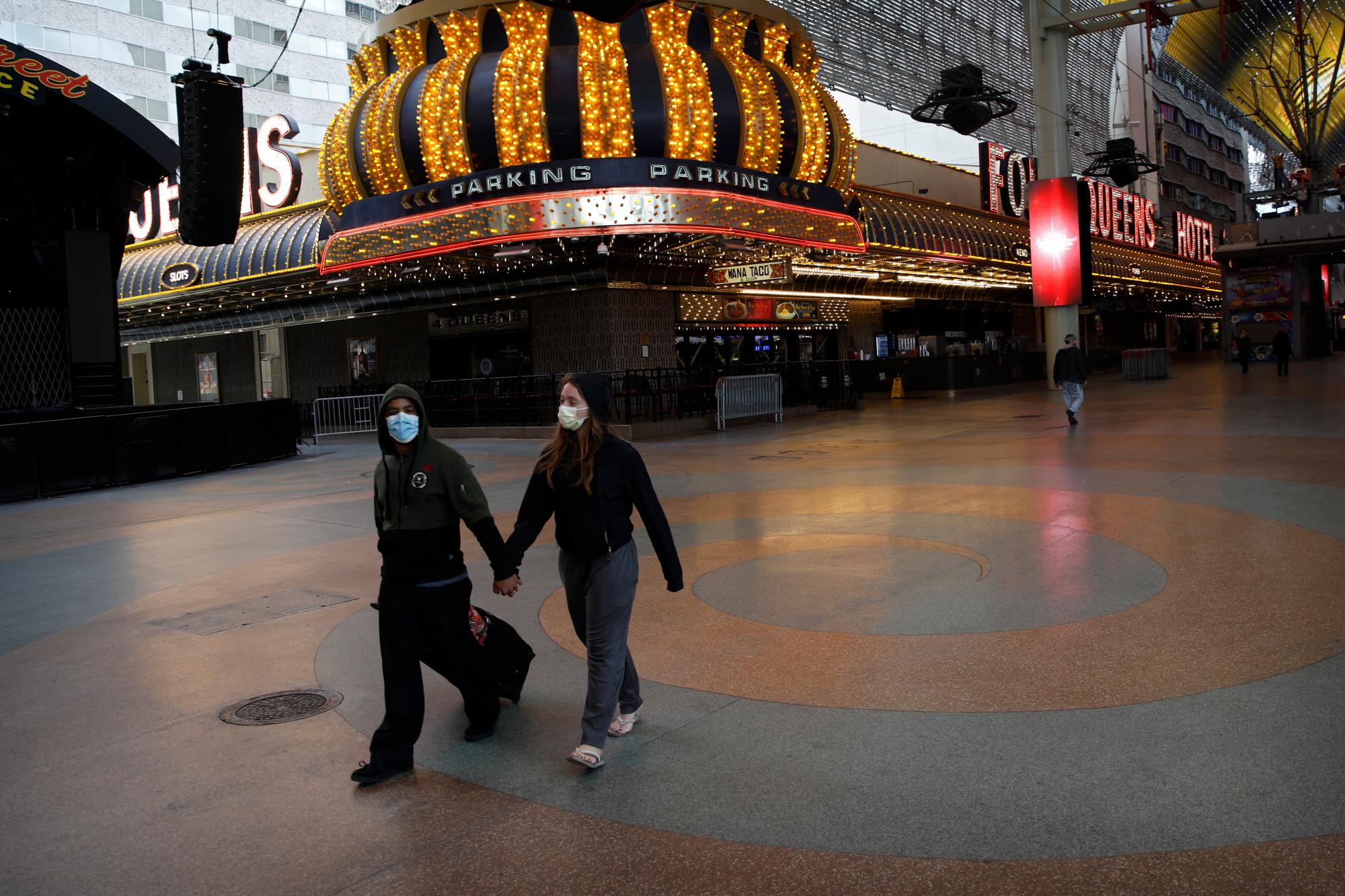 Una pareja camina por una calle Fremont generalmente concurrida después de que se ordenó el cierre de los casinos debido al brote de coronavirus, el miércoles 18 de marzo de 2020, en Las Vegas. 