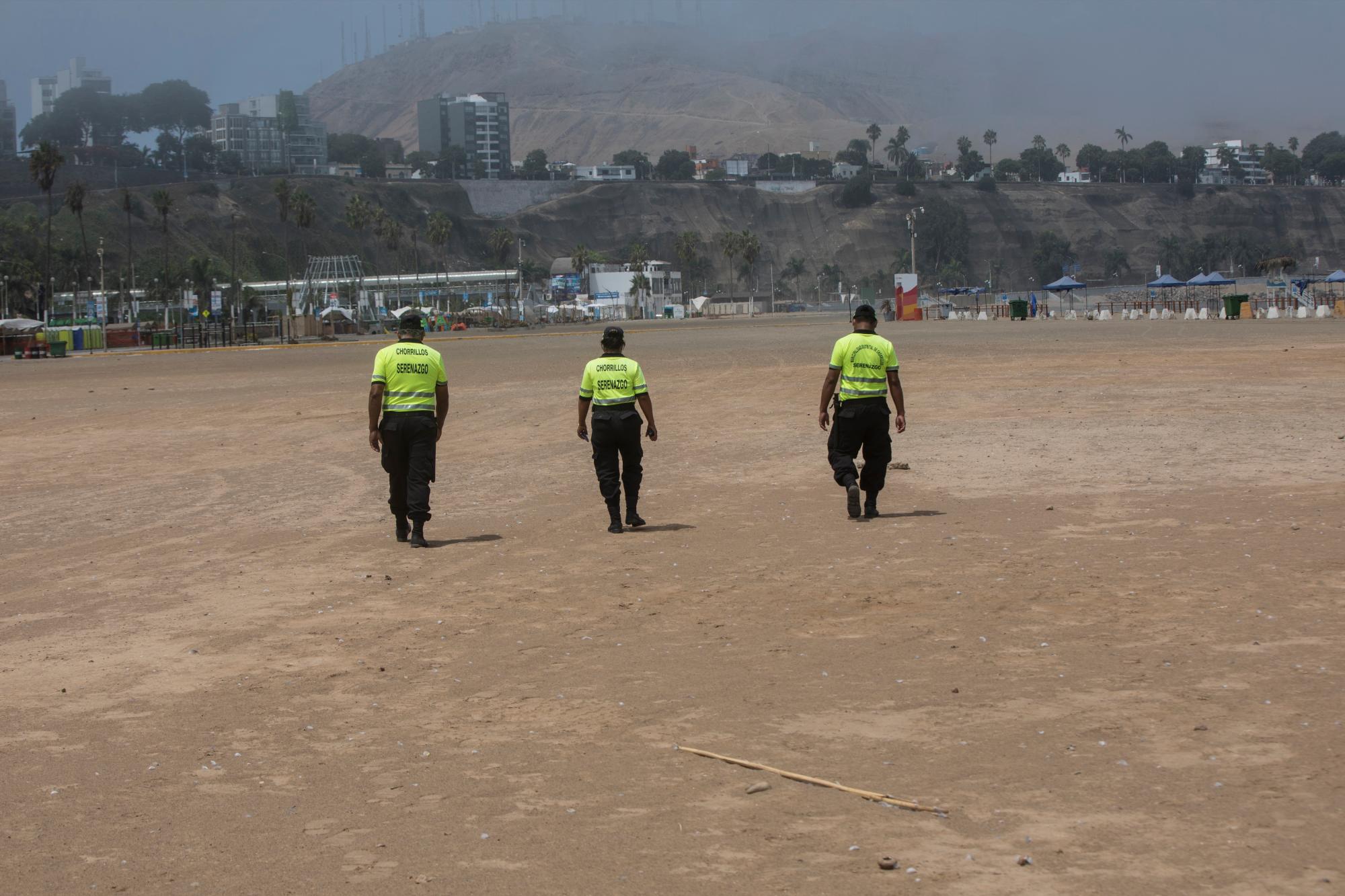 En esta imagen, tomada el 24 de marzo de 2020, agentes de policía caminan por la playa de Agua Dulce, vacía en los últimos días del verano austral, para advertir a los bañistas, como medida contra la propagación contra del nuevo coronavirus, en Lima, Perú. (AP Foto/Rodrigo Abd)