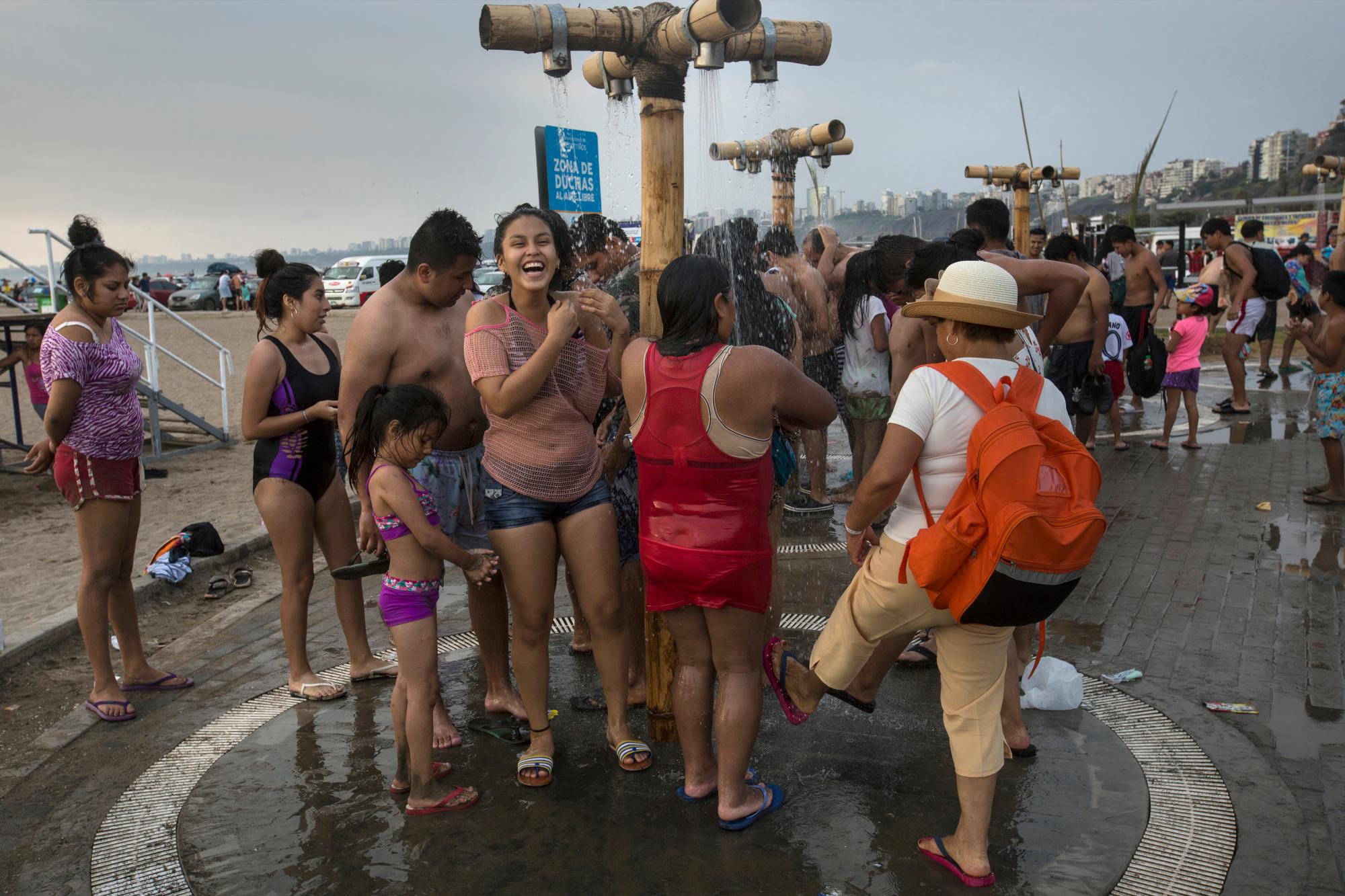 En esta imagen, tomada el 15 de febrero de 2020, bañistas se sacan la arena y la salitre tras bañarse en aguas del Océano Pacífico en la playa de Agua Dulce, en Lima, Perú. (AP Foto/Rodrigo Abd)