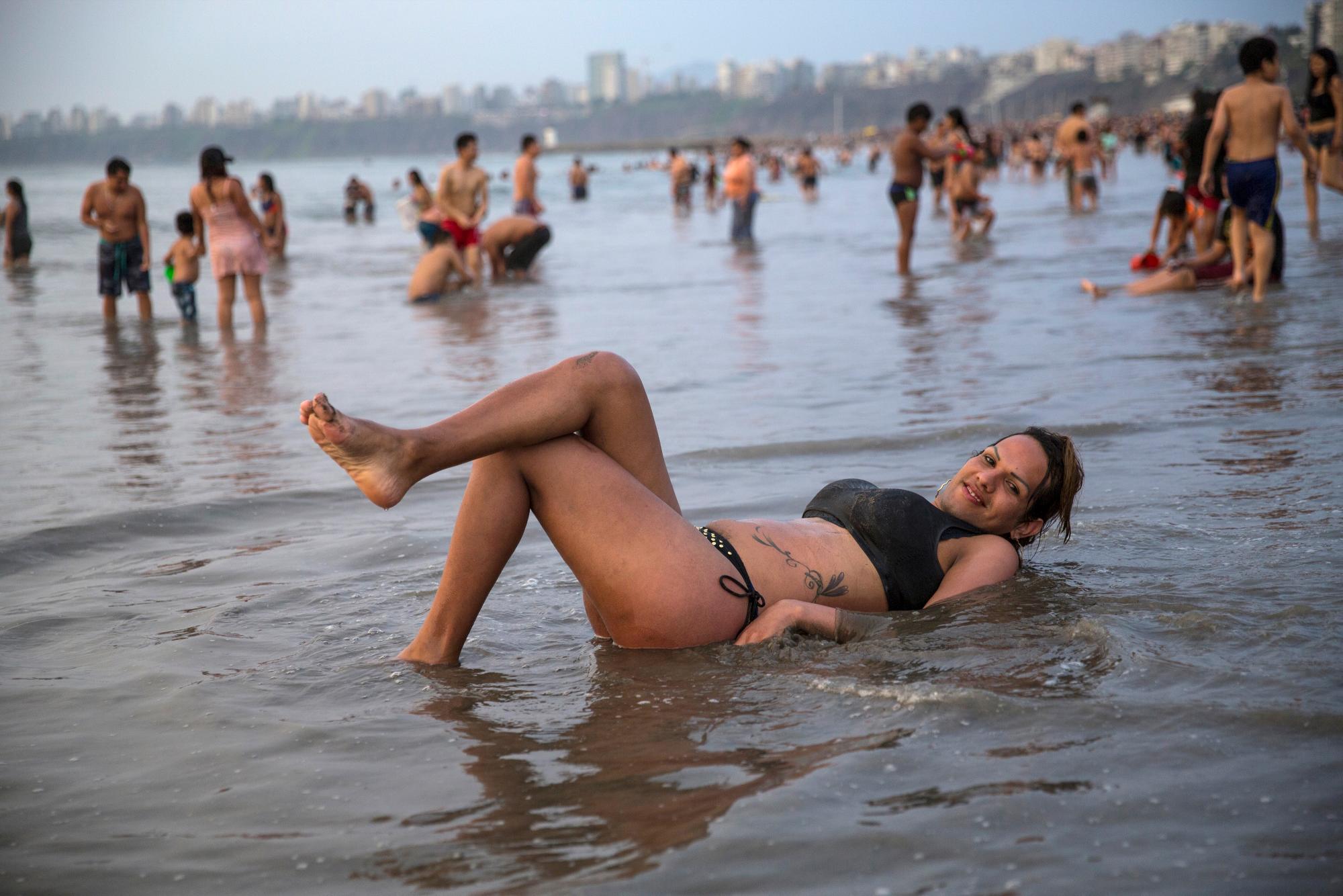 En esta imagen, tomada el 16 de febrero de 2020, Natalia, una migrante transexual venezolana, posa tumbada en la orilla de la playa de Agua Dulce, en Lima, Perú. (AP Foto/Rodrigo Abd)