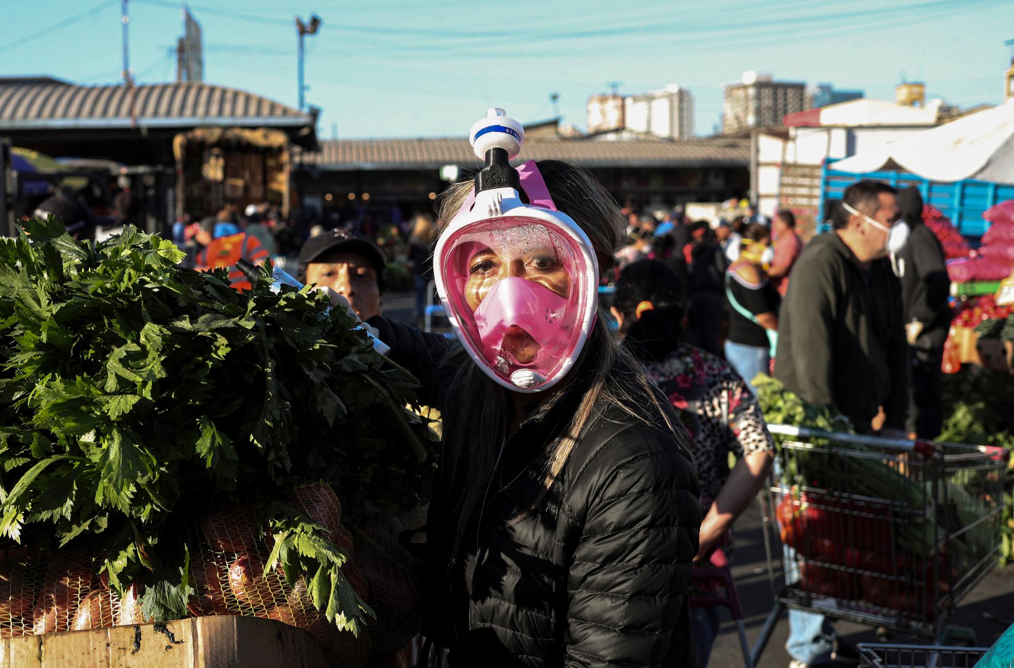 En esta imagen, tomada el 2 de abril de 2020, una compradora utiliza una máscara de snorkel como medida de protección contra el coronavirus mientras compra en el mercado de La Vega, en Santiago, Chile. En Chile, que suma más de 2.500 casos desde que confirmó el primero el 3 de marzo, muchos de los contagios se localizaron en vecindarios de clase media-alta, entre gente que estuvo recientemente en Europa, especialmente en Italia. (AP Foto/Esteban Félix)