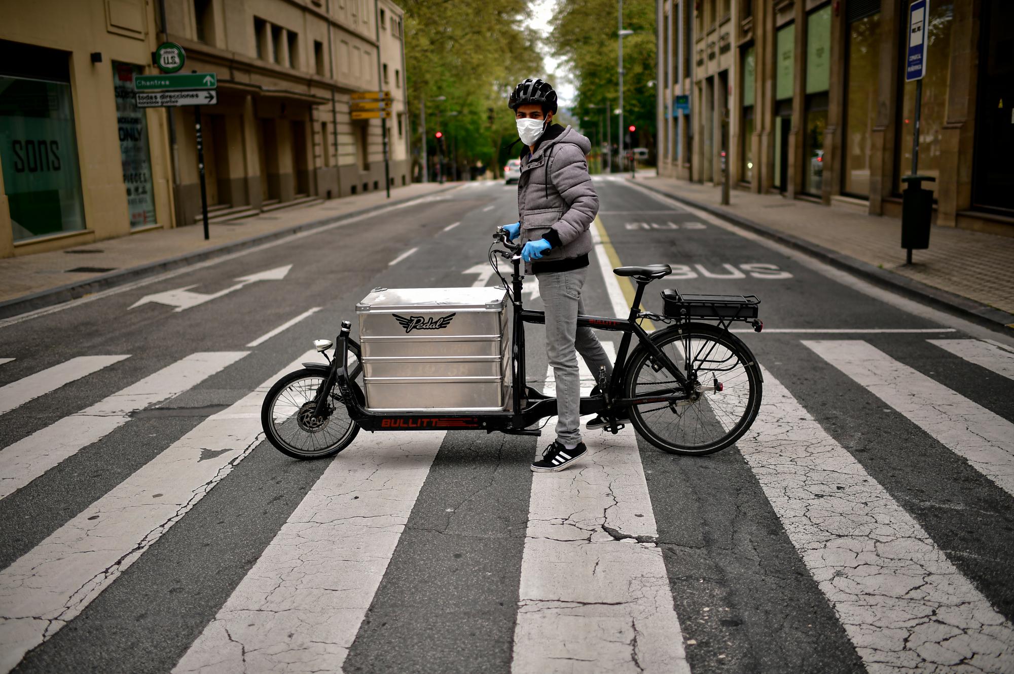 En esta imagen del jueves 16 de abril de 2020, Sidi Hasan posa para una foto con su bicicleta de reparto en Pamplona, en el norte de España. (AP Foto/Álvaro Barrientos)