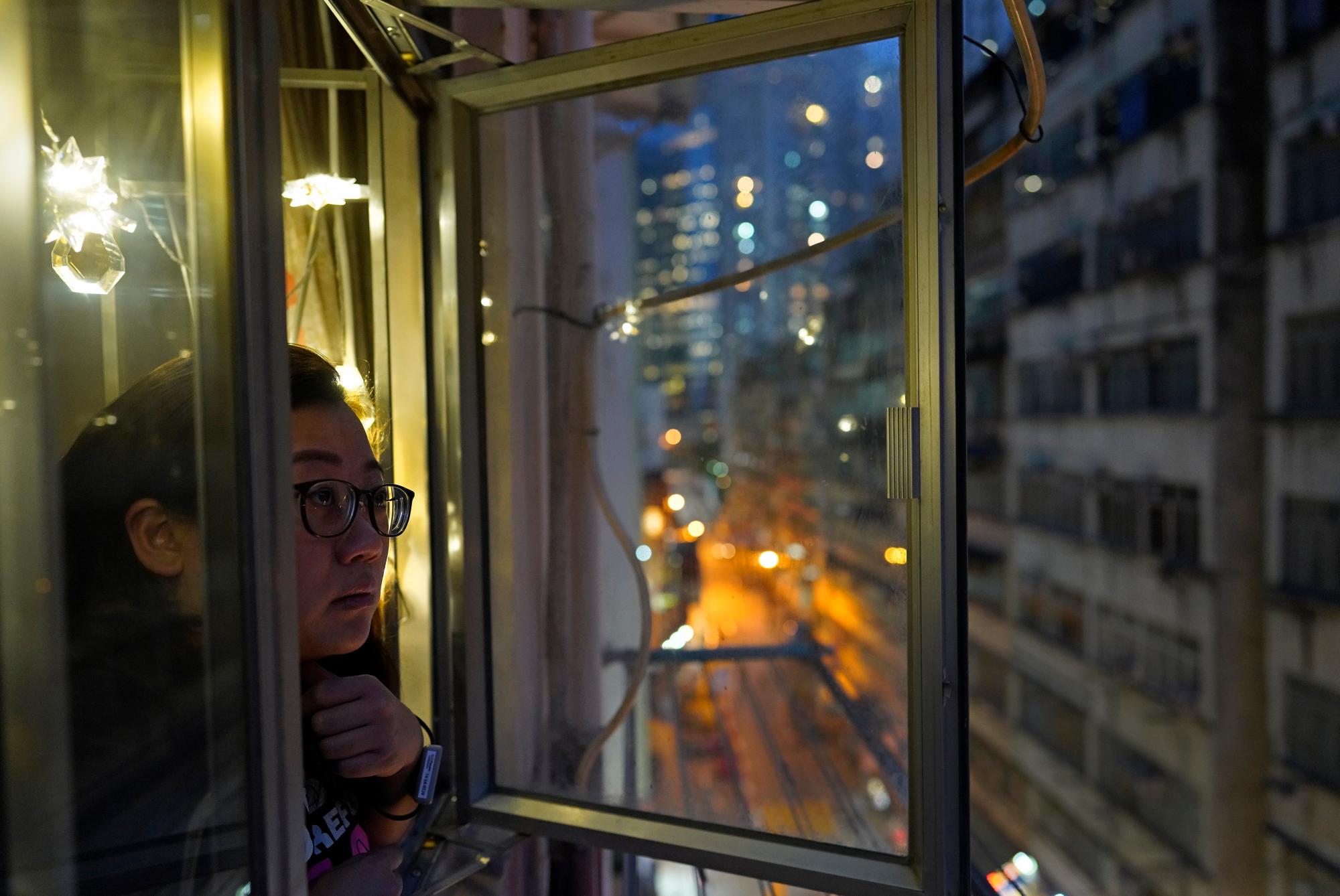 La reportera de Associated Press, Zen Soo, asoma la cabeza por la ventana para tomar aire fresco mientras cumple su cuarentena de 14 días en su hogar en Hong Kong, el 17 de abril de 2020. Hong Kong emitió pulseras de cuarentena para monitorear a los residentes que regresan de la ciudad mientras cumplen su obligación. Cuarentena de 14 días, en un intento por frenar las transmisiones locales de COVID-19 durante la pandemia. (Foto AP / Vincent Yu)