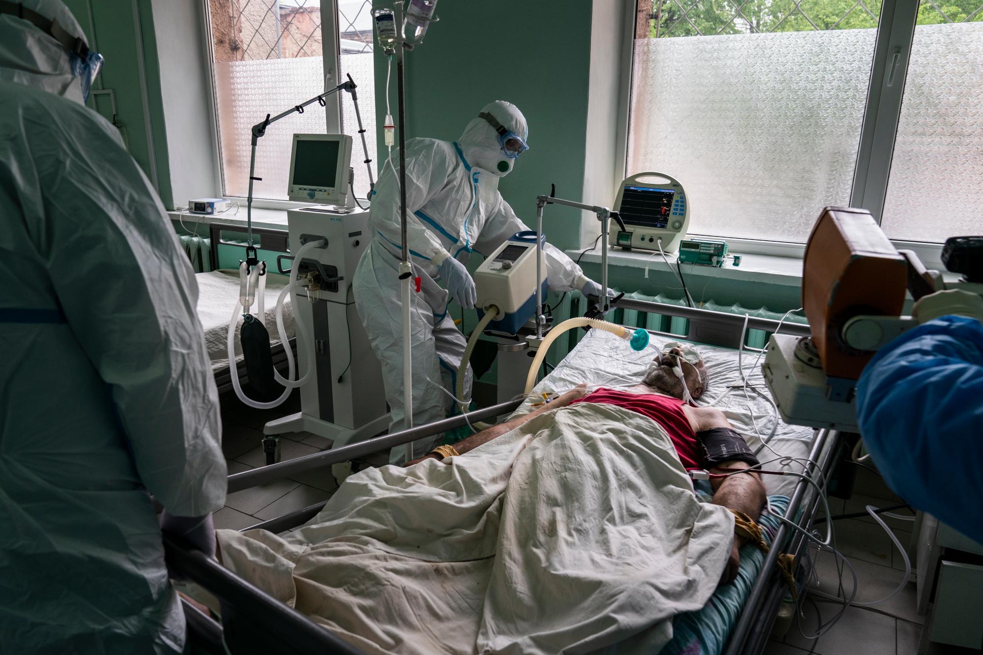 En esta foto tomada el lunes 4 de mayo de 2020, los médicos, vestidos con trajes especiales para protegerse contra el coronavirus, preparan a un paciente con coronavirus para recibir una radiografía de sus pulmones en una unidad de cuidados intensivos en un hospital regional en Chernivtsi, Ucrania. El problemático sistema de salud de Ucrania ha sido abrumado por COVID-19, a pesar de que ha reportado un número relativamente bajo de casos. (Foto AP / Evgeniy Maloletka)