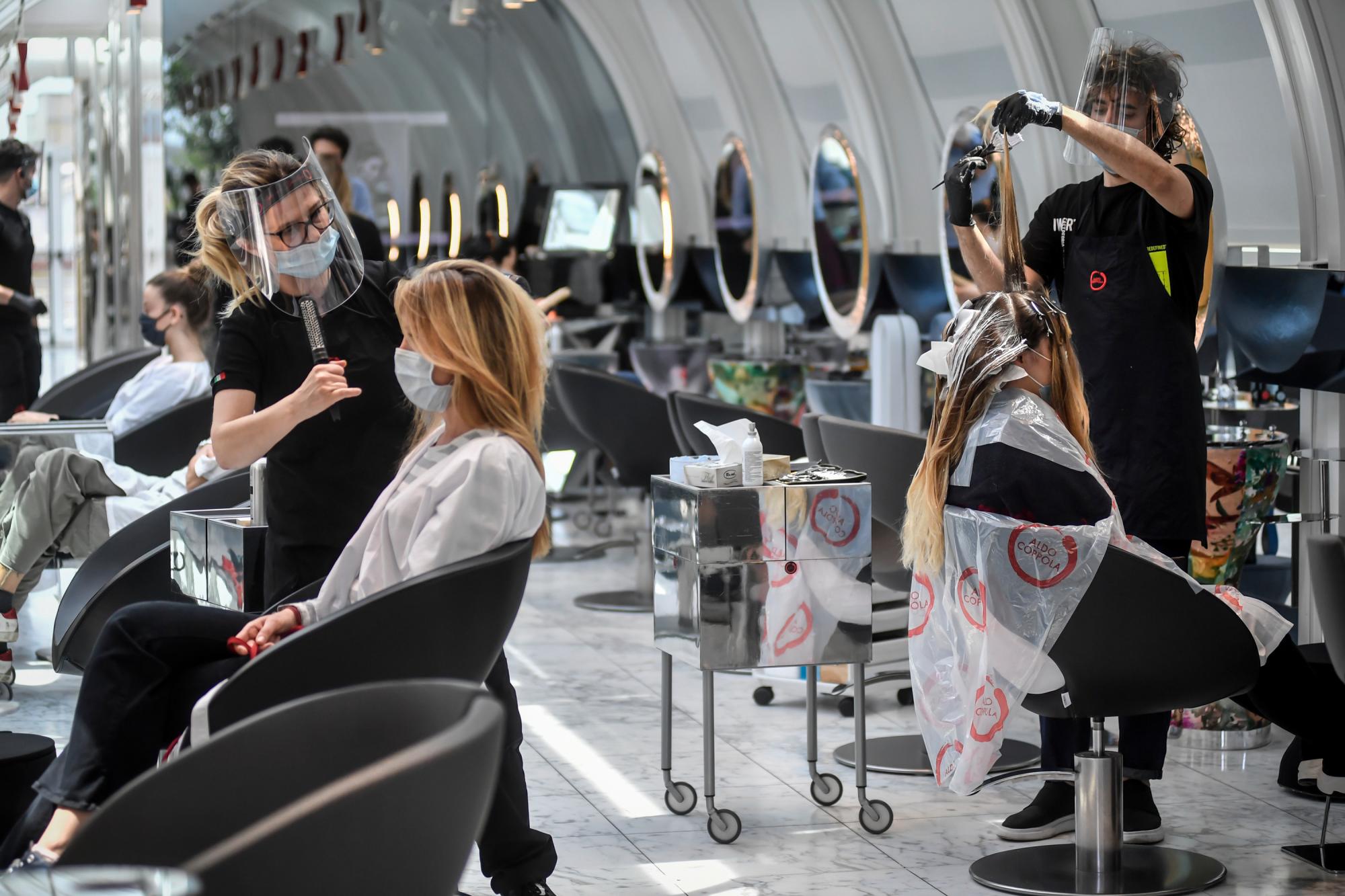 Los clientes se arreglan el cabello en una peluquería en Milán, Italia, el lunes 18 de mayo de 2020, ya que Italia está levantando lentamente las restricciones sanitarias después de un bloqueo de coronavirus de dos meses. (Claudio Furlan / LaPresse a través de AP)