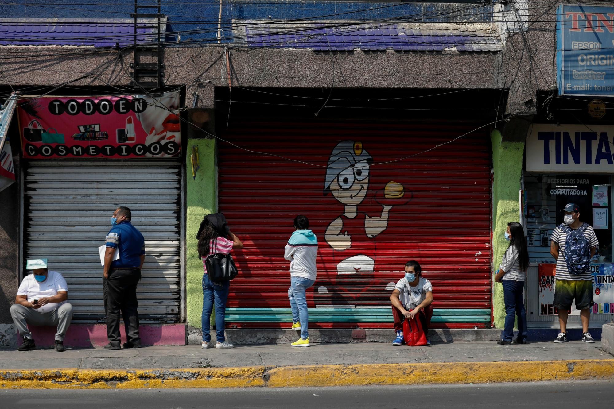 La gente espera en una fila socialmente distanciada para ingresar a un banco, en Ecatepec, un suburbio de la Ciudad de México, el miércoles 20 de mayo de 2020. La Ciudad de México, una de las ciudades más grandes del mundo y el epicentro de la epidemia de coronavirus del país, comenzará una reapertura gradual El 1 de junio, su alcalde dijo el miércoles, incluso cuando nuevas infecciones diarias seguían estableciendo récords. (Foto AP / Rebecca Blackwell)