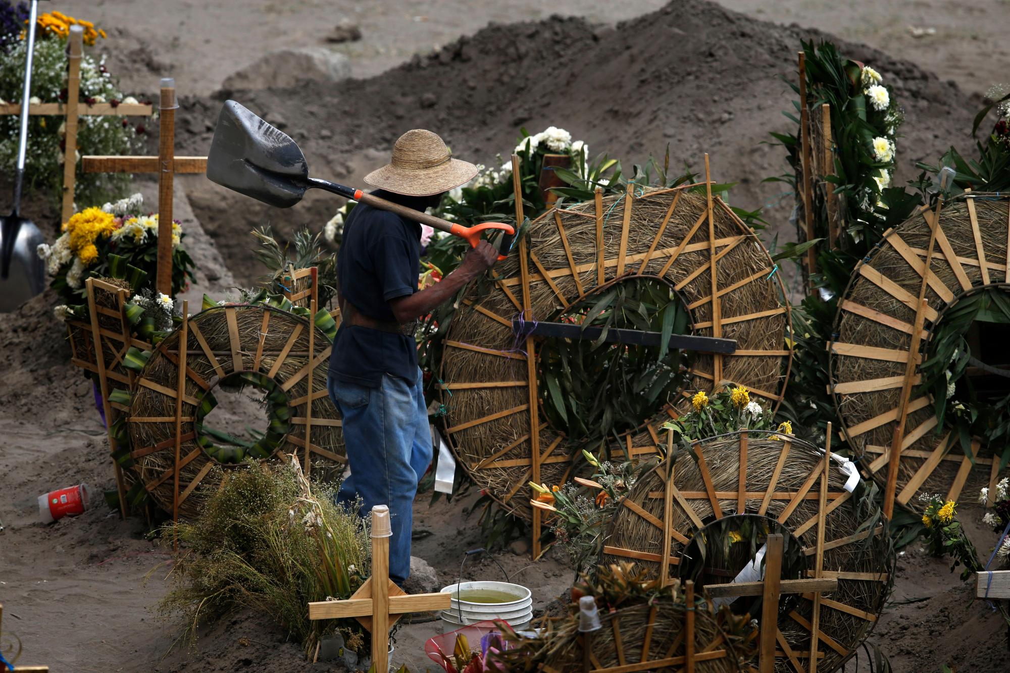 Un trabajador camina entre tumbas en el cementerio municipal Valle de Chalco recientemente construido, construido para dar cabida al aumento de muertes en medio de la nueva pandemia de coronavirus, en las afueras de la Ciudad de México, el jueves 21 de mayo de 2020. (Foto AP / Marco Ugarte)