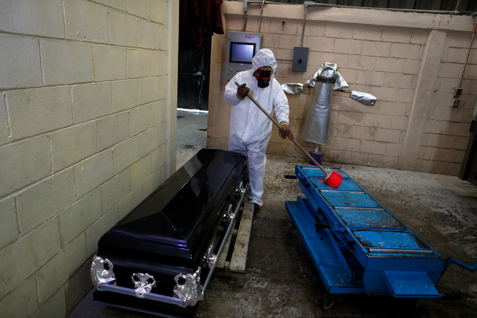 Un trabajador limpia una camilla con desinfectante después de que el cuerpo de una persona que murió de coronavirus fue colocado en el horno para cremación, en los mausoleos de San Cristóbal en Ecatepec, Estado de México, parte del área metropolitana de la Ciudad de México, el jueves 21 de mayo de 2020. Cuando se manejan casos de COVID-19 confirmado o sospechoso, los trabajadores de crematorios usan trajes protectores, respiradores de cara completa y guantes, y mantienen protocolos rígidos de desinfección. (Foto AP / Rebecca Blackwell)