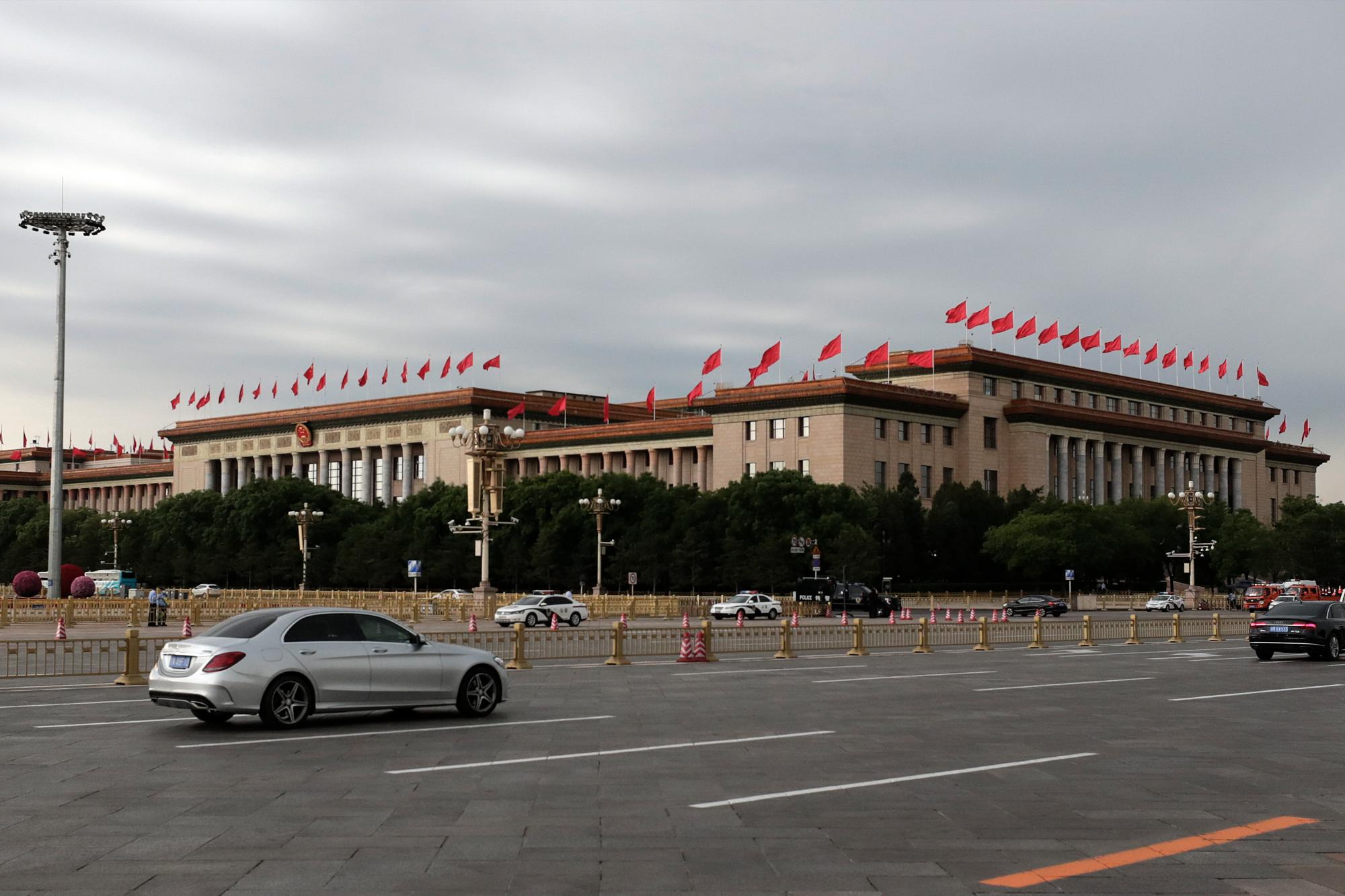 Los vehículos pasan por el Gran Salón del Pueblo antes de una sesión plenaria del Congreso Nacional del Pueblo (APN) de China en Beijing, el lunes 25 de mayo de 2020. (Foto AP / Andy Wong)