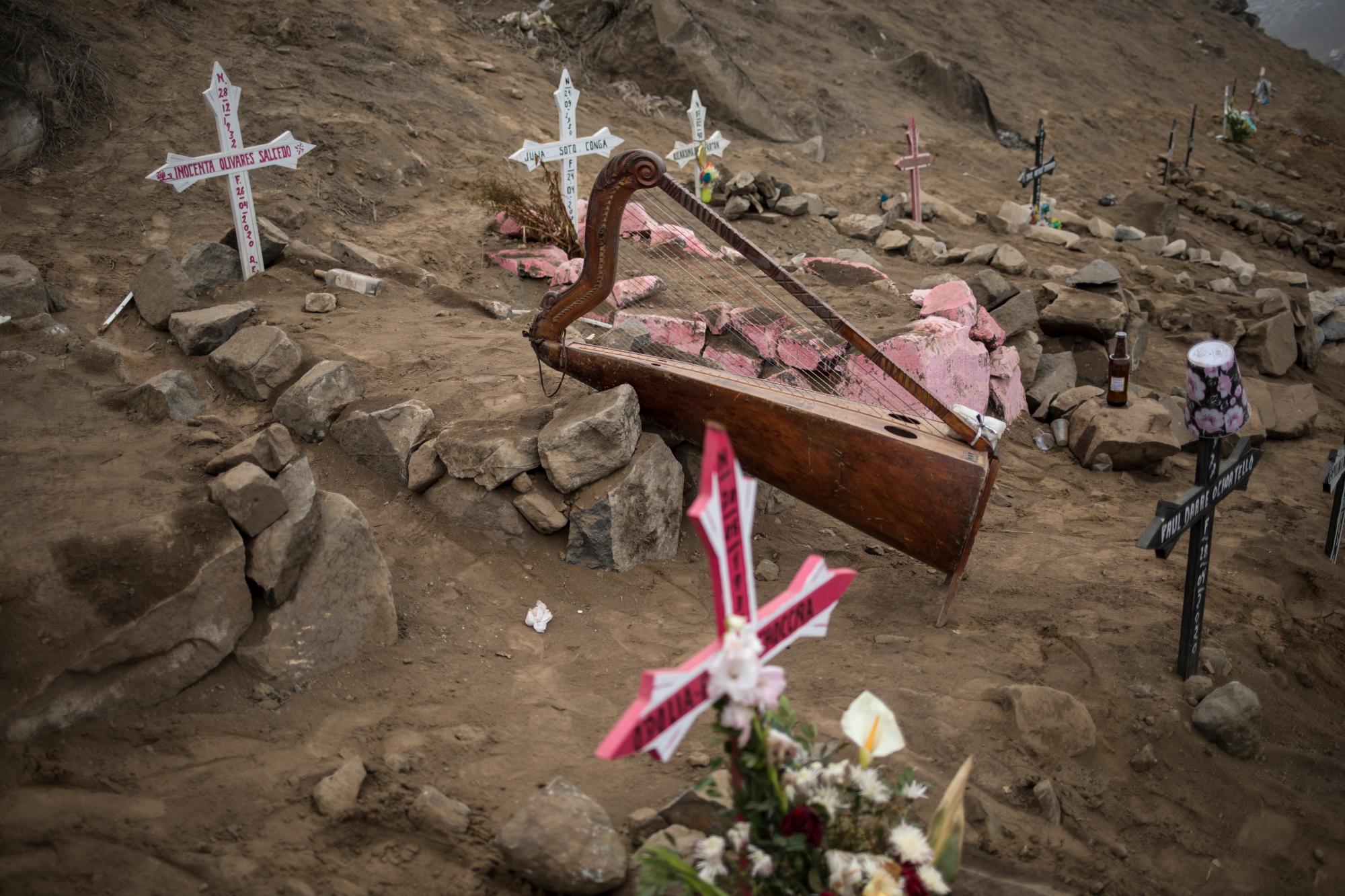 El arpa del músico Charlie Juárez se encuentra entre las tumbas de las víctimas de COVID-19 en el cementerio de Nueva Esperanza en las afueras de Lima, Perú, el martes 26 de mayo de 2020. (Foto AP / Rodrigo Abd)
