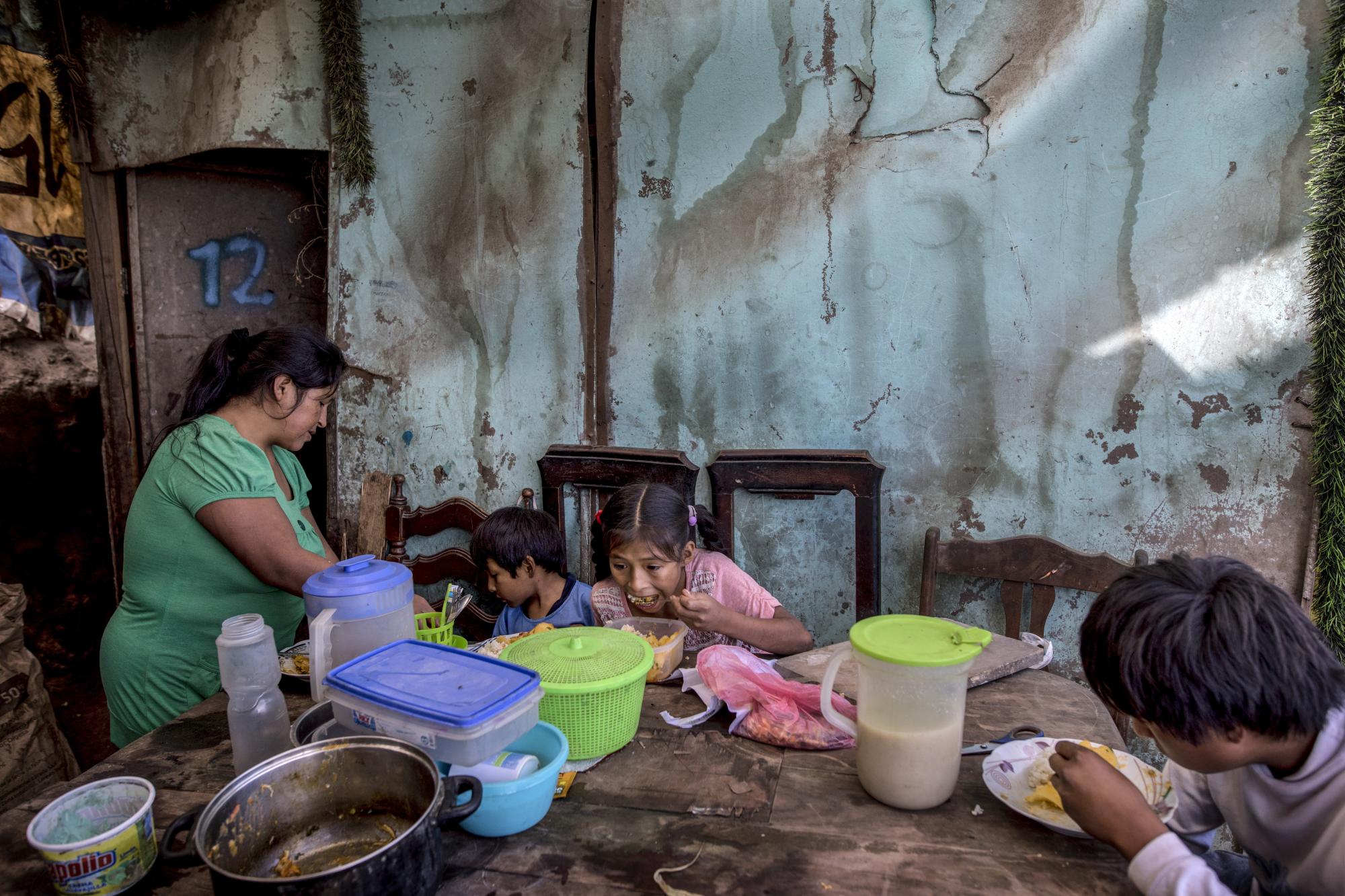 Los tres hijos de Consuelo Pascacio, Estiben, de 4; Estefany, de 11, y Javier, de 14, comen un estofado de arroz con pollo que recogió en una olla comunitaria, en su casa en el barrio Nueva Esperanza de Lima (AP Foto/Rodrigo Abd)