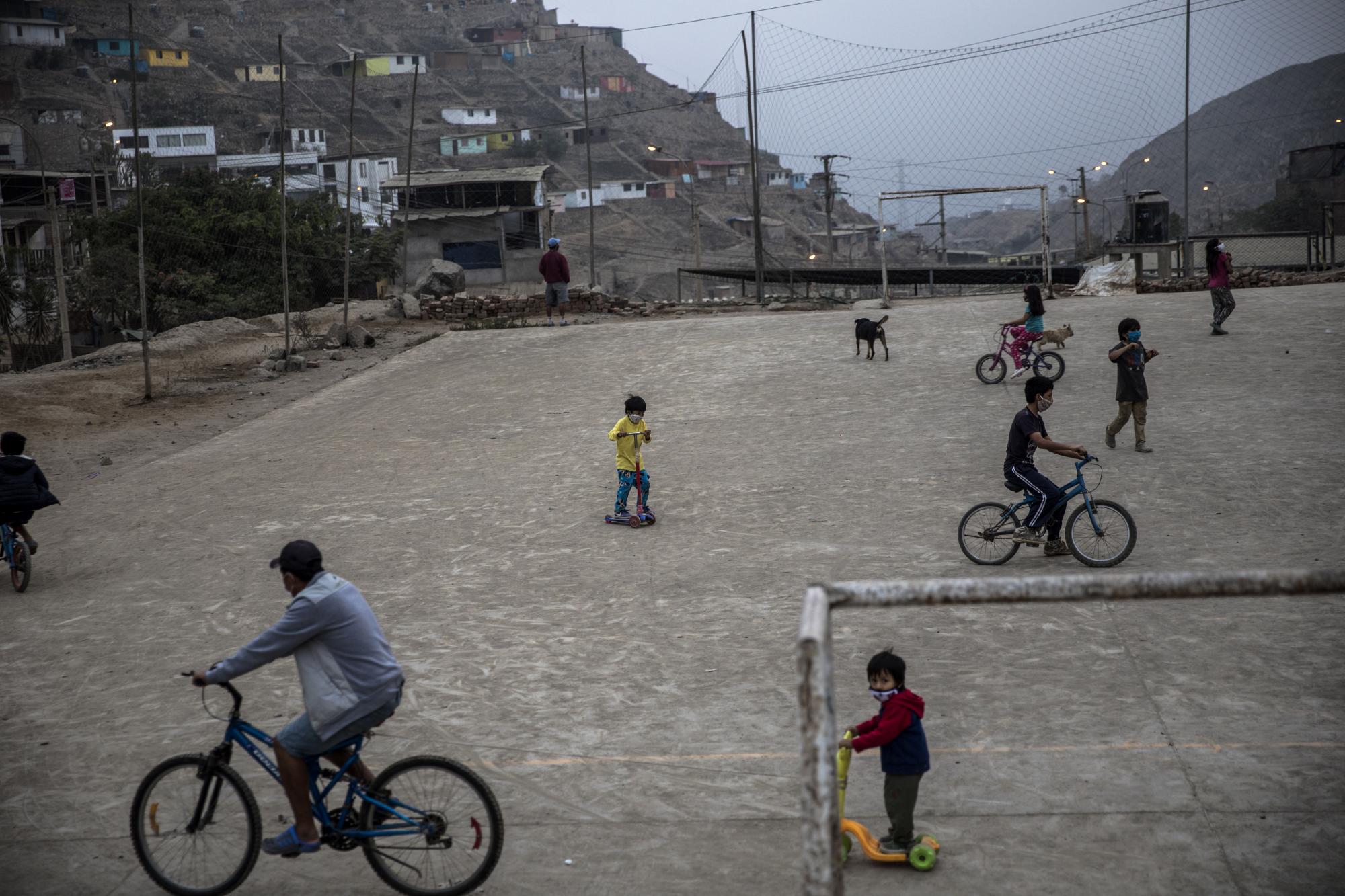 Los residentes montan bicicletas y scooters en un campo de fútbol comunitario en el barrio de Nueva Esperanza de Lima, Perú. (AP Foto/Rodrigo Abd)