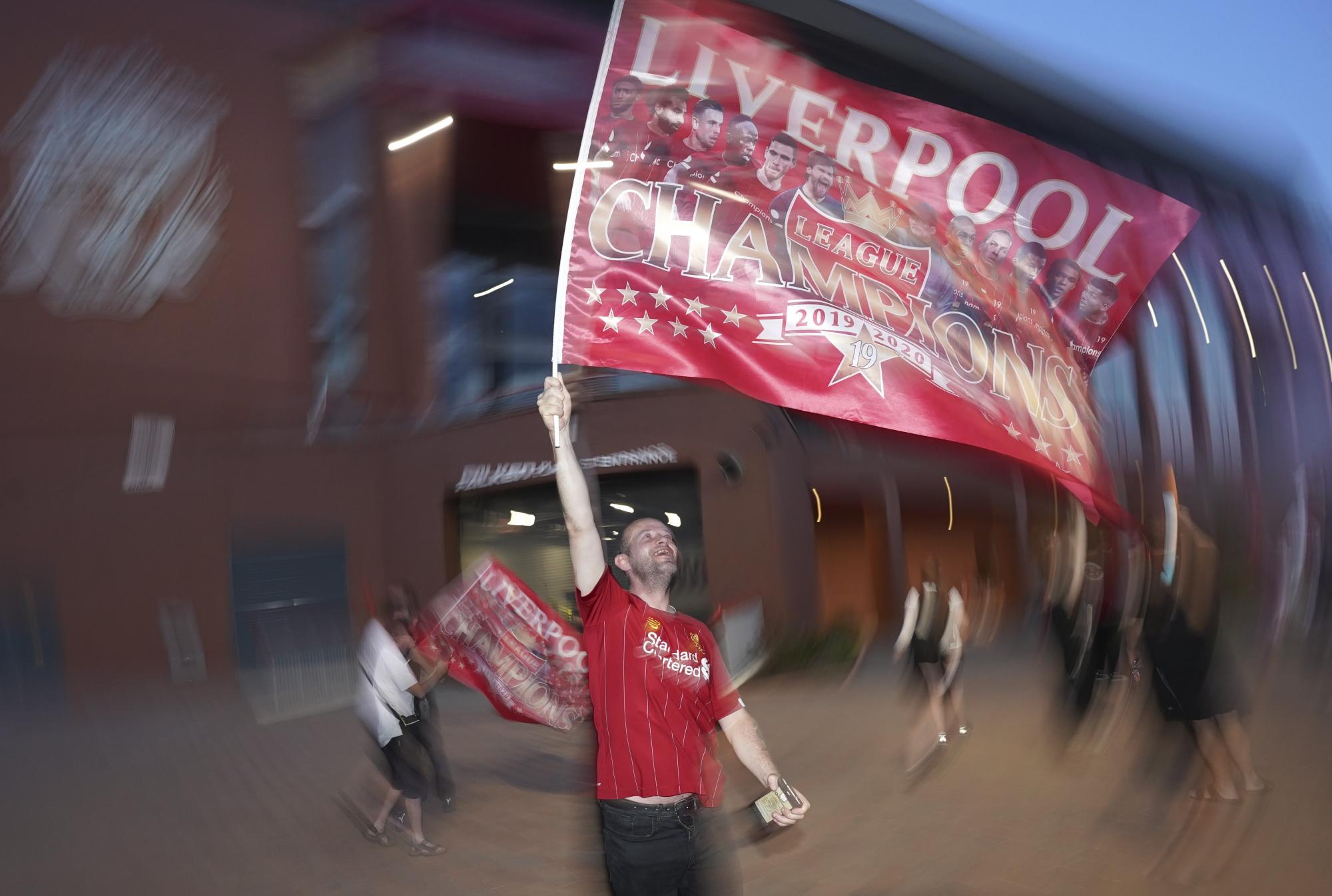 Un fanático ondea una bandera del Liverpool frente al Anfield Stadium durante la celebración decimonoveno título  en la liga inglesa  (AP photo/Jon Super)