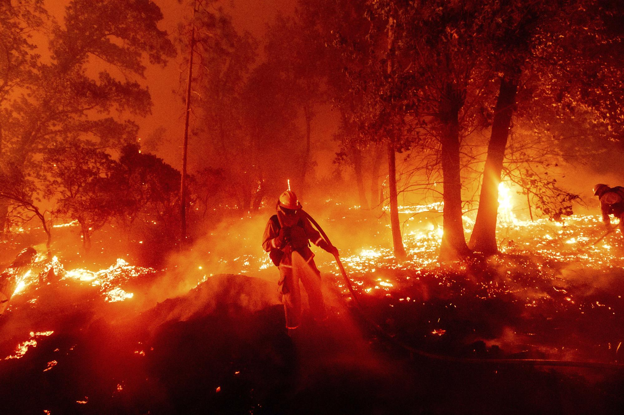 Un bombero lucha contra las llamas que amenazan el vecindario de Cascadel Woods en el condado de  Madera en California. (AP Photo/Noah Berger)