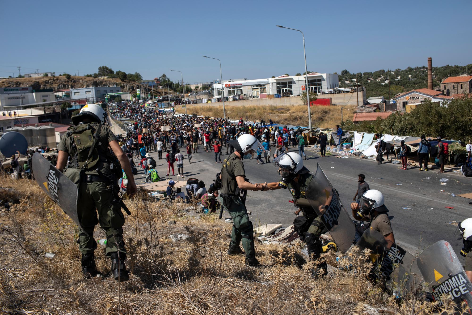 Migrantes participan en una manifestación mientras la policía antidisturbios bloquea la carretera cerca de la ciudad de Mytilene, en la isla nororiental de Lesbos, Grecia, el viernes 11 de septiembre de 2020. 