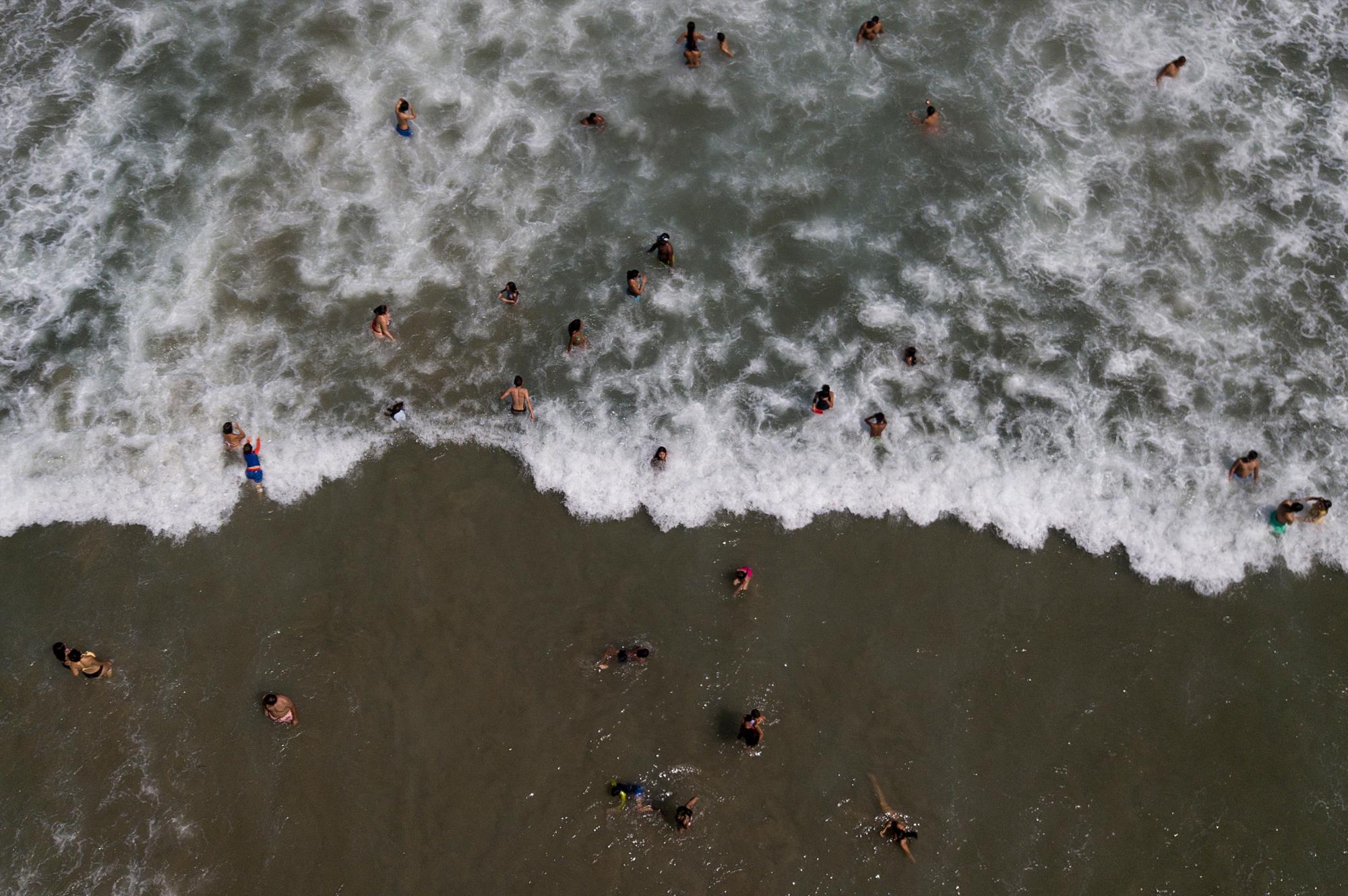 La gente nada en la playa Los Ángeles después de su reciente reapertura después de una cuarentena para enfrentar la pandemia del nuevo coronavirus en La Guaira, Venezuela, el viernes 23 de octubre de 2020. 