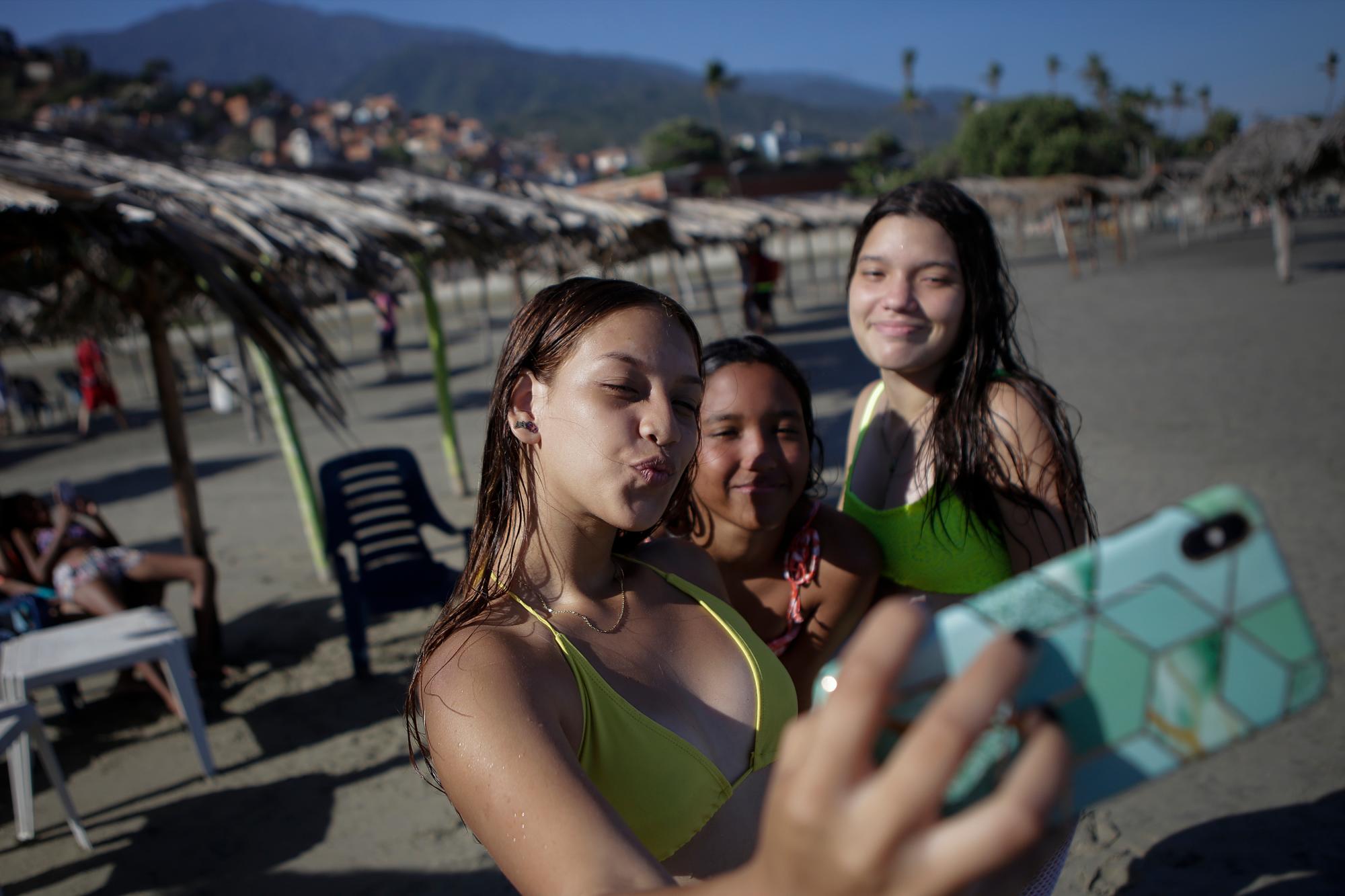 Un grupo de amigas se toma fotos en la playa La Última después de su reciente reapertura tras una cuarentena para enfrentar la pandemia del nuevo coronavirus en La Guaira, Venezuela, el viernes 23 de octubre de 2020. 