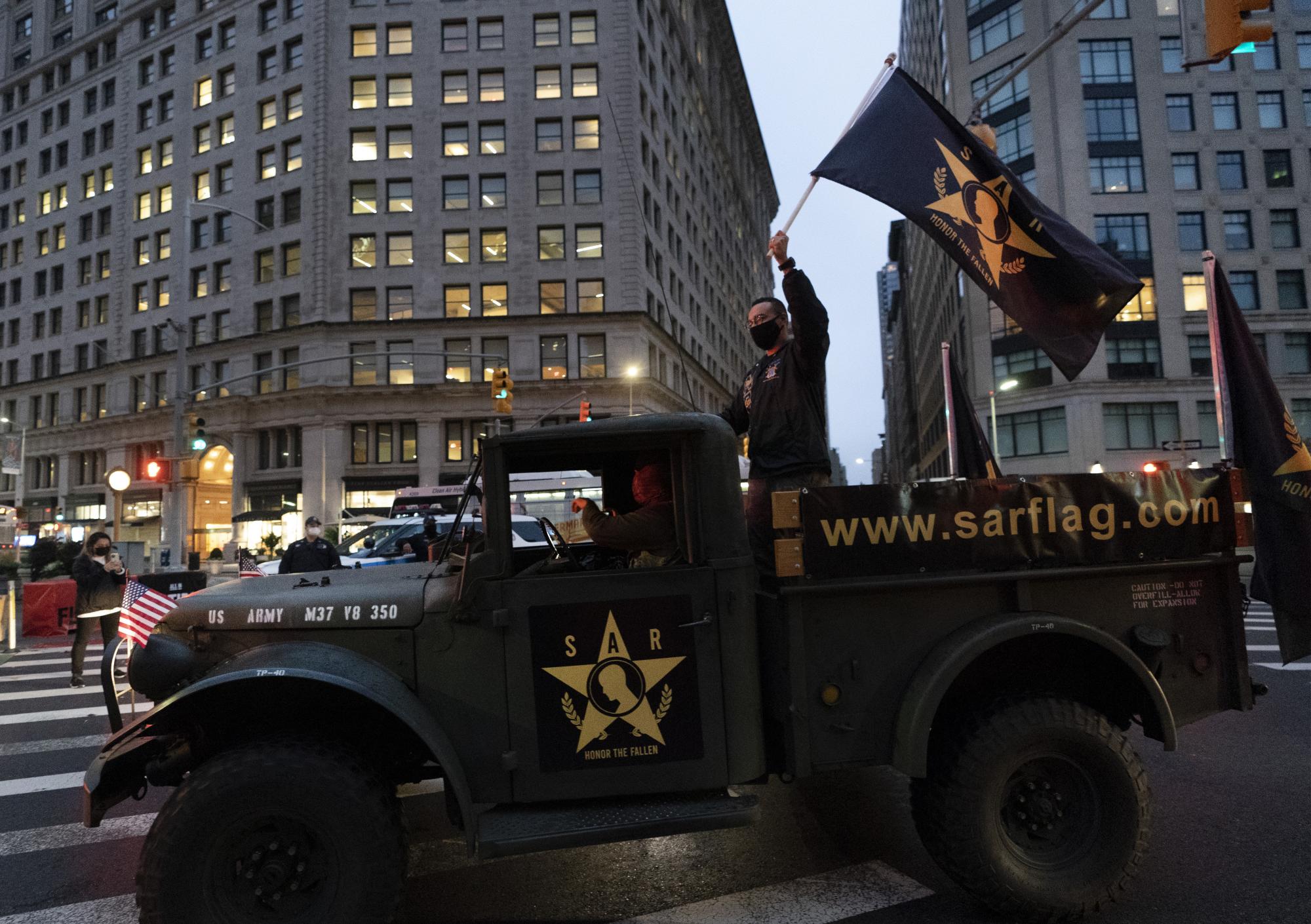 Un hombre agita una bandera en un vehículo militar que formó parte del desfile por el día de los veteranos, celebrado en la ciudad de Nueva York. AP Photo/Mark Lennihan