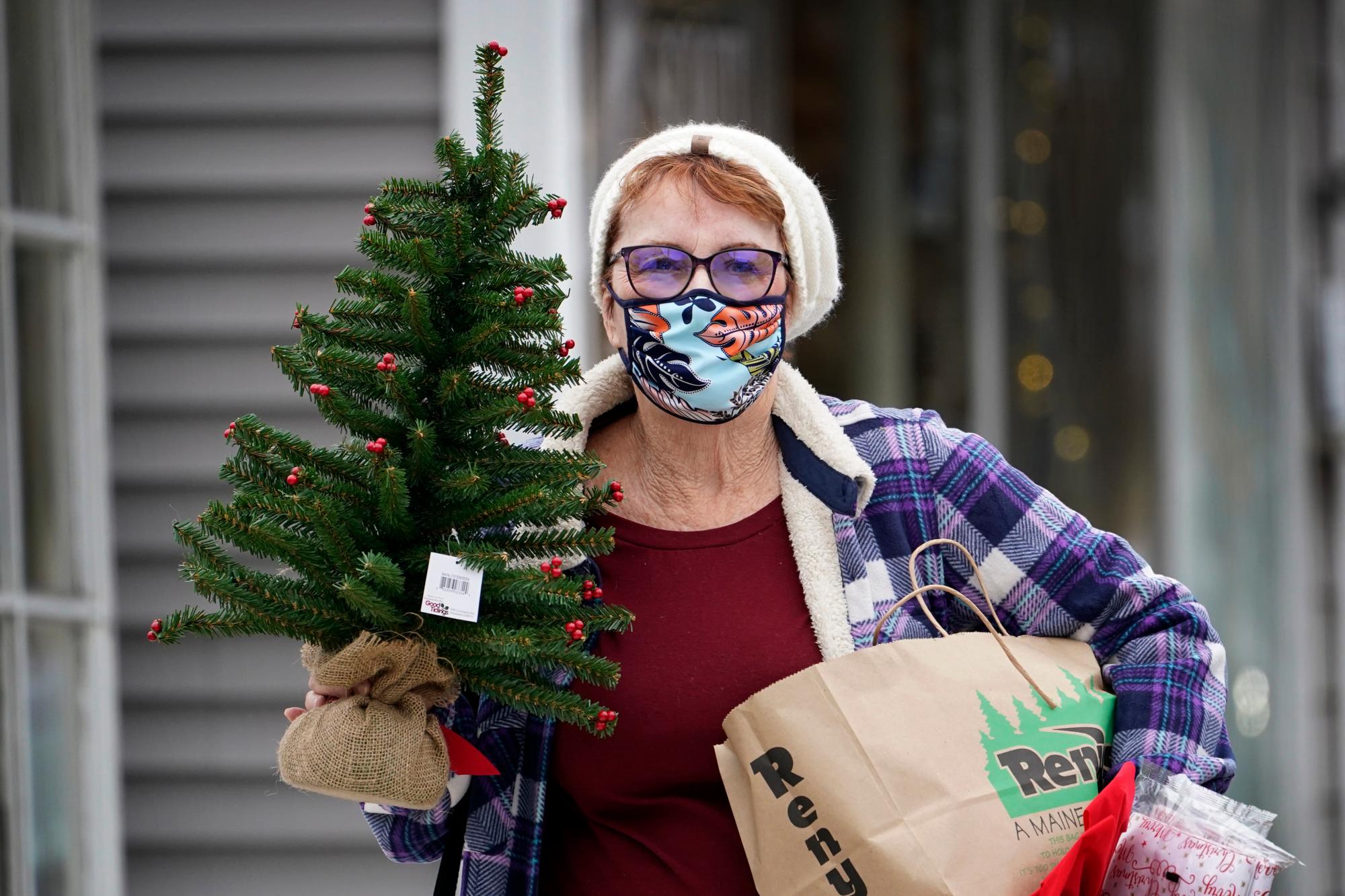 Suzanne West, de Harrison, Maine, usa una cubierta facial para ayudar a prevenir la propagación del coronavirus después de comprar decoraciones navideñas, el viernes 13 de noviembre de 2020 en Bridgton, Maine. El estado informó un nuevo número récord de casos de COVID-19 el viernes. 