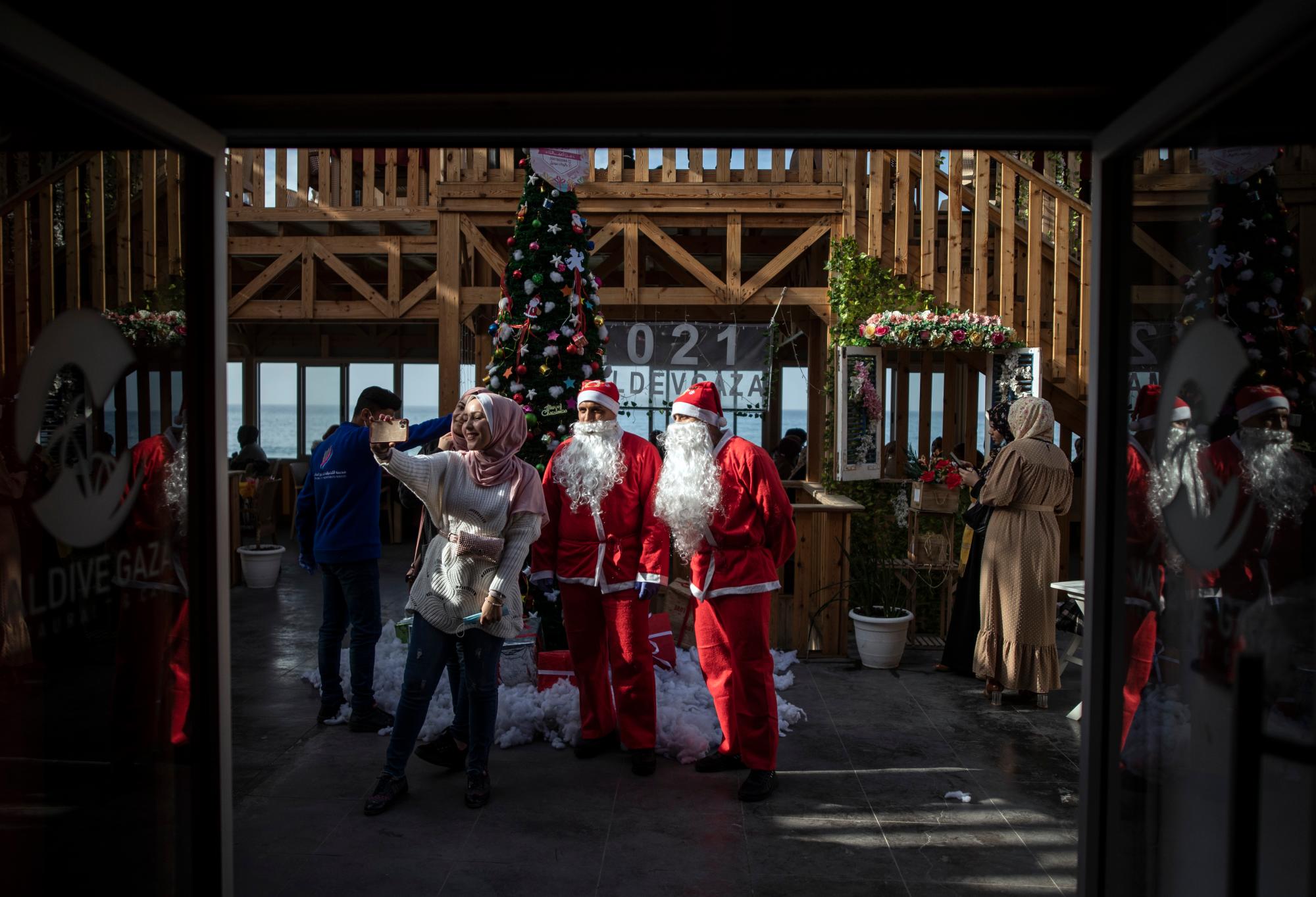 Palestinos se toman una selfie con camareros vestidos como Papá Noel en un restaurante en la playa de la ciudad de Gaza, el domingo 13 de diciembre de 2020.