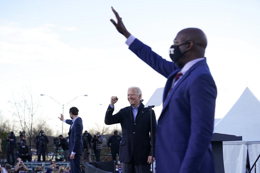 Raphael Warnock alza su mano en señal de victoria en un acto encabezado por el presidente electo Joe  Biden (AP Photo/Carolyn Kaste)