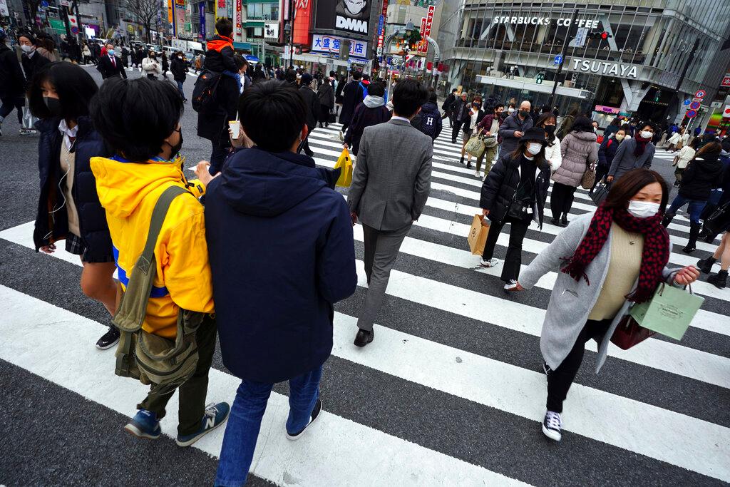 Personas con máscaras protectoras para ayudar a frenar la propagación del coronavirus caminan por los cruces peatonales en el área de Shibuya en Tokio. La capital japonesa confirmó este martes más de 1200 nuevos casos de coronavirus.