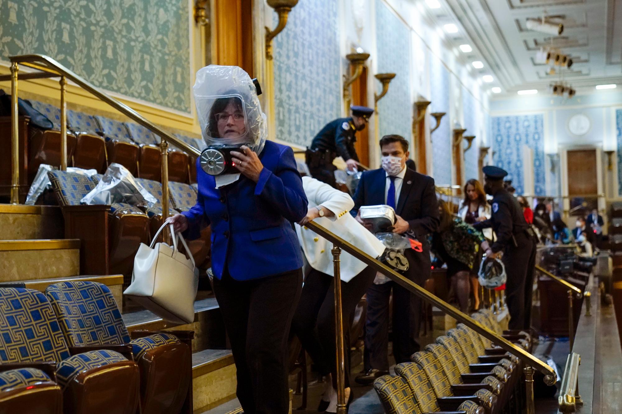 Personas se refugian en la galería de la Cámara mientras los manifestantes intentan irrumpir en la Cámara de la Cámara en el Capitolio de los Estados Unidos el miércoles 6 de enero de 2021 en Washington.