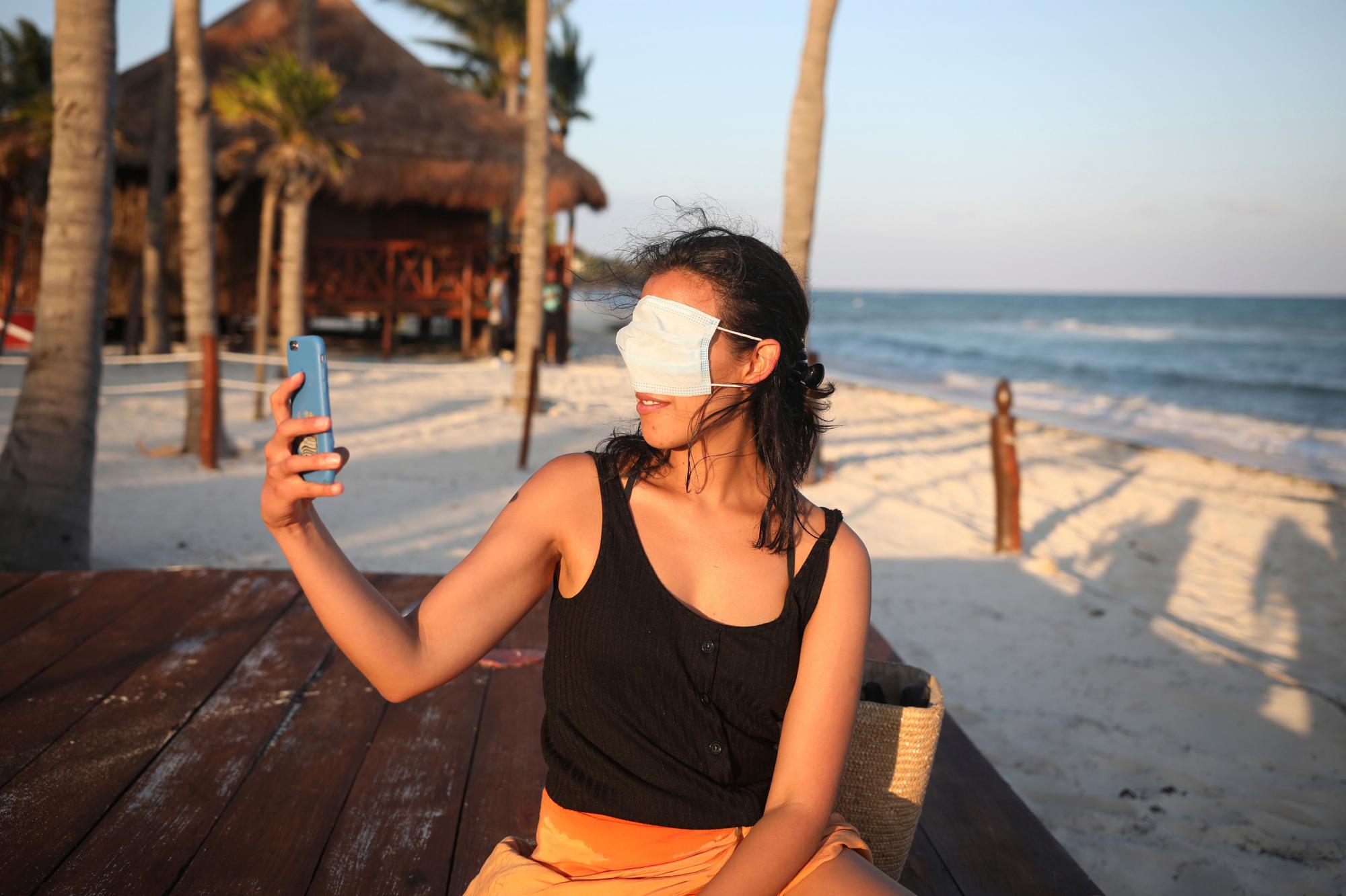 Romina Montoya, residente en la Ciudad de México, se toma una selfie graciosa con una mascarilla sobre los ojos y la nariz, en Playa del Carmen, en el estado de Quintana Roo, México, el 6 de enero de 2021. Aumenta la preocupación porque el éxito de la crucial campaña turística invernal pueda ser efímero por el aumento de los casos de COVID-19 tanto en México como en Estados Unidos. 