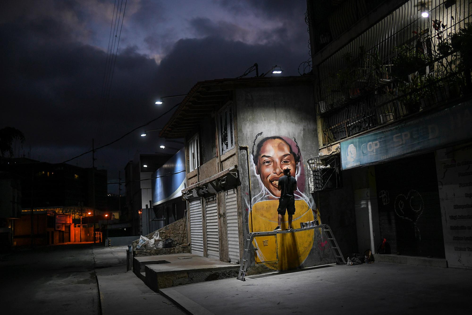 El artista callejero Wolfgang Salazar trabaja en un mural con la imagen de la atleta venezolana Yulimar Rojas, en el vecindario de Boleita, en Caracas, Venezuela, el 2 de enero de 2021. Salazar dijo que eligió pintar a Rojas porque representa el potencial de grandeza venezolano. 