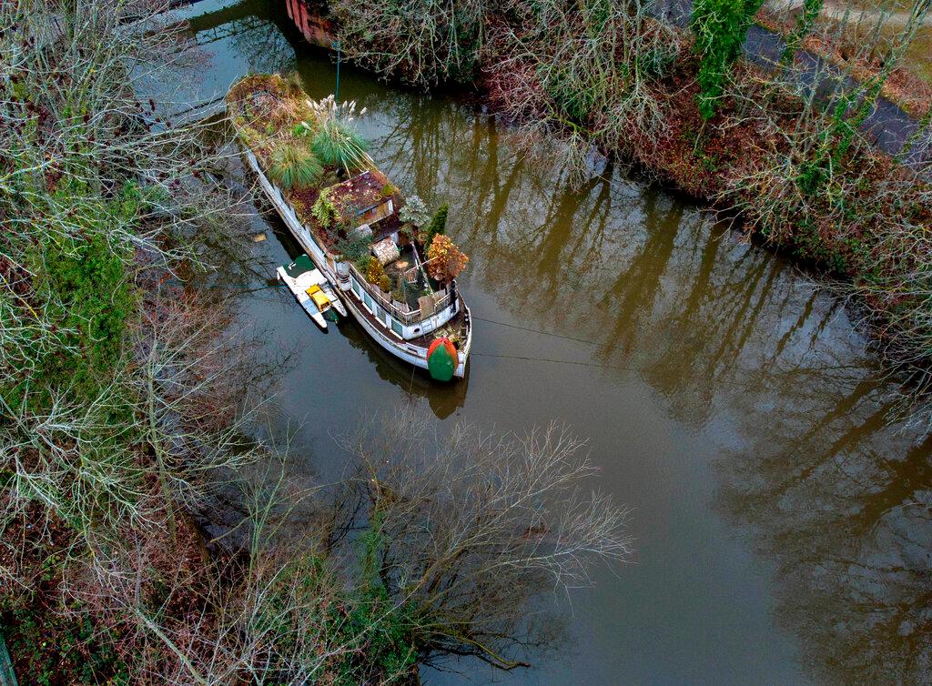 Un barco abandonado cubierto de césped y plantas se asienta sobre un brazo lateral del río Main en Frankfurt, Alemania.