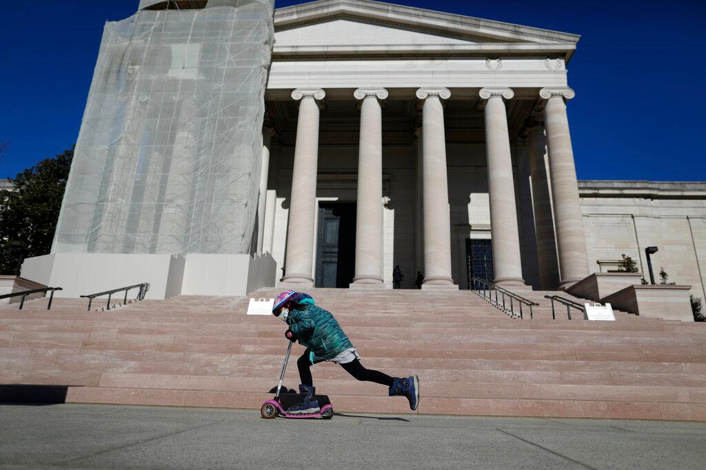 Una niña pasa en una scooter frente a la Galería Nacional de Arte, el sábado 23 de enero de 2021, en Washington.
