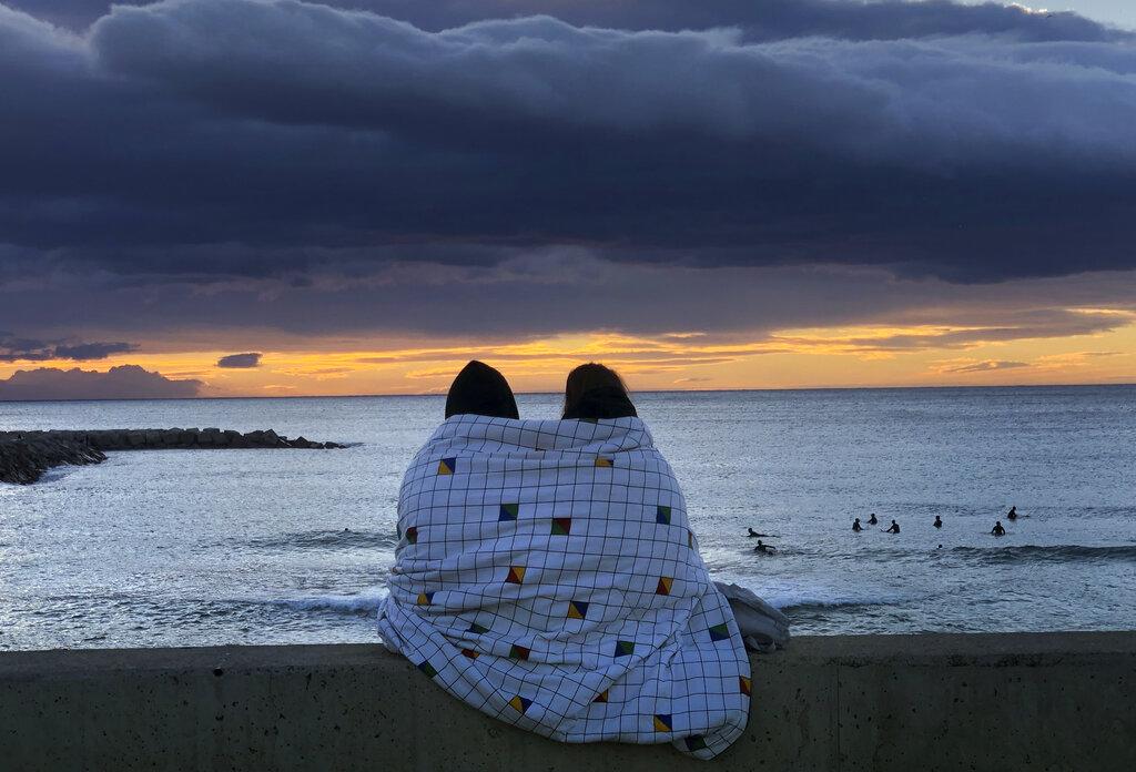 Una pareja contempla la salida del sol sobre el Mar Mediterráneo en la ciudad de Barcelona, España (AP Photo/Emilio Morenatti)