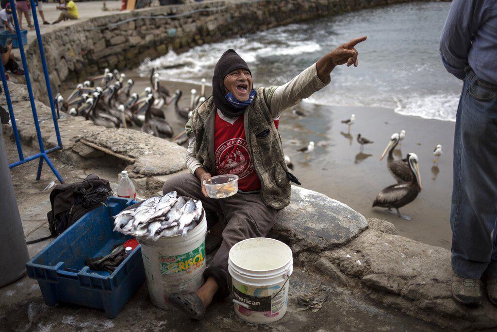 Willy Ricas, un pescador peruano de 56 años, bromea con un amigo mientras come su almuerzo en una zona costera de la ciudad de Lima, en Perú (AP Photo/Rodrigo Abd)