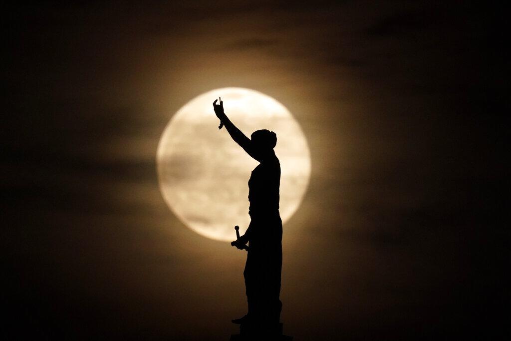 Una estatua de la dama de la justicia en una corte de Missouri es captada en silueta con la luna llena de fondo (AP Photo/Charlie Riedel)