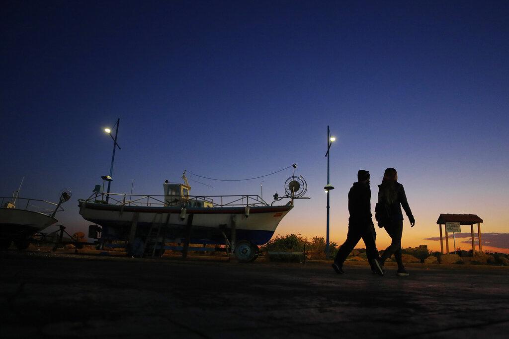 Un hombre y una mujer caminan en las cercanías de un muelle en Chipre (AP Photo/Petros Karadjias)