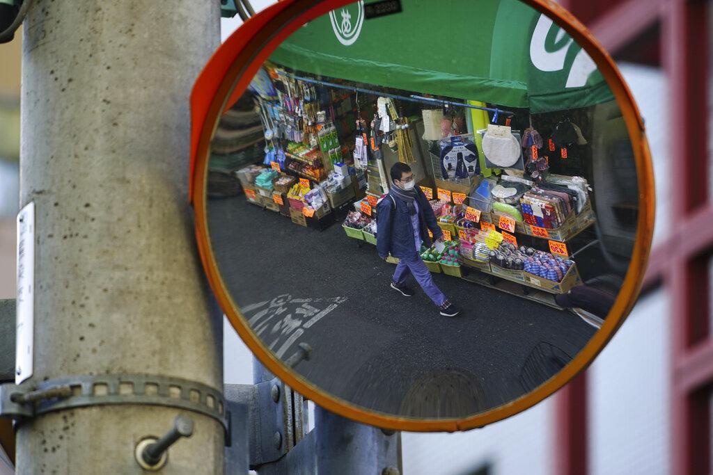 Un hombre camina en una calle de Tokio portando una mascarilla para protegerse del COVID-19 (AP Photo/Eugene Hoshiko)