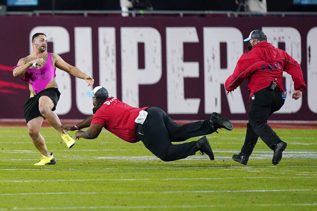 Miembros de la seguridad tratan de atrapar a un fanático que se lanzó al terreno de juego durante el compromiso que enfrentó a Tampa Bay y Kansas City en el Súper Bowl LV (AP Photo/Mark Humphrey)
