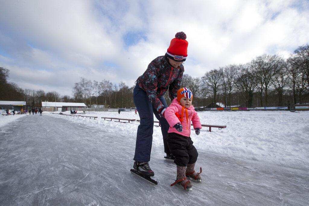 Una madre enseña a su pequeña hija a patinar sobre el hielo en una pista al aire libre en Holanda (AP Photo/Peter Dejong)