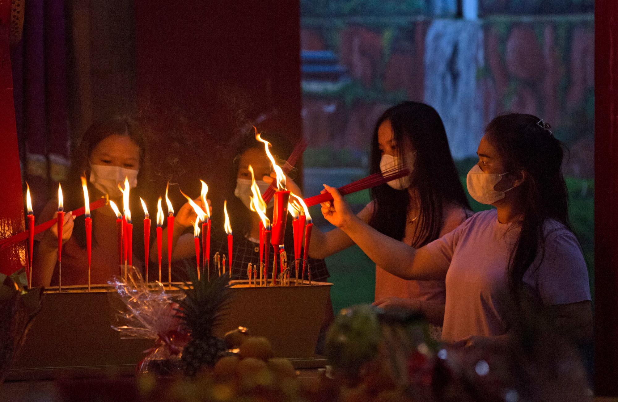 Adoradores de etnia china que usan máscaras faciales para ayudar a frenar la propagación del brote de coronavirus, durante la celebración de la víspera del Año Nuevo Lunar en un templo en Medan, Sumatra del Norte, Indonesia, el viernes 12 de febrero de 2021.