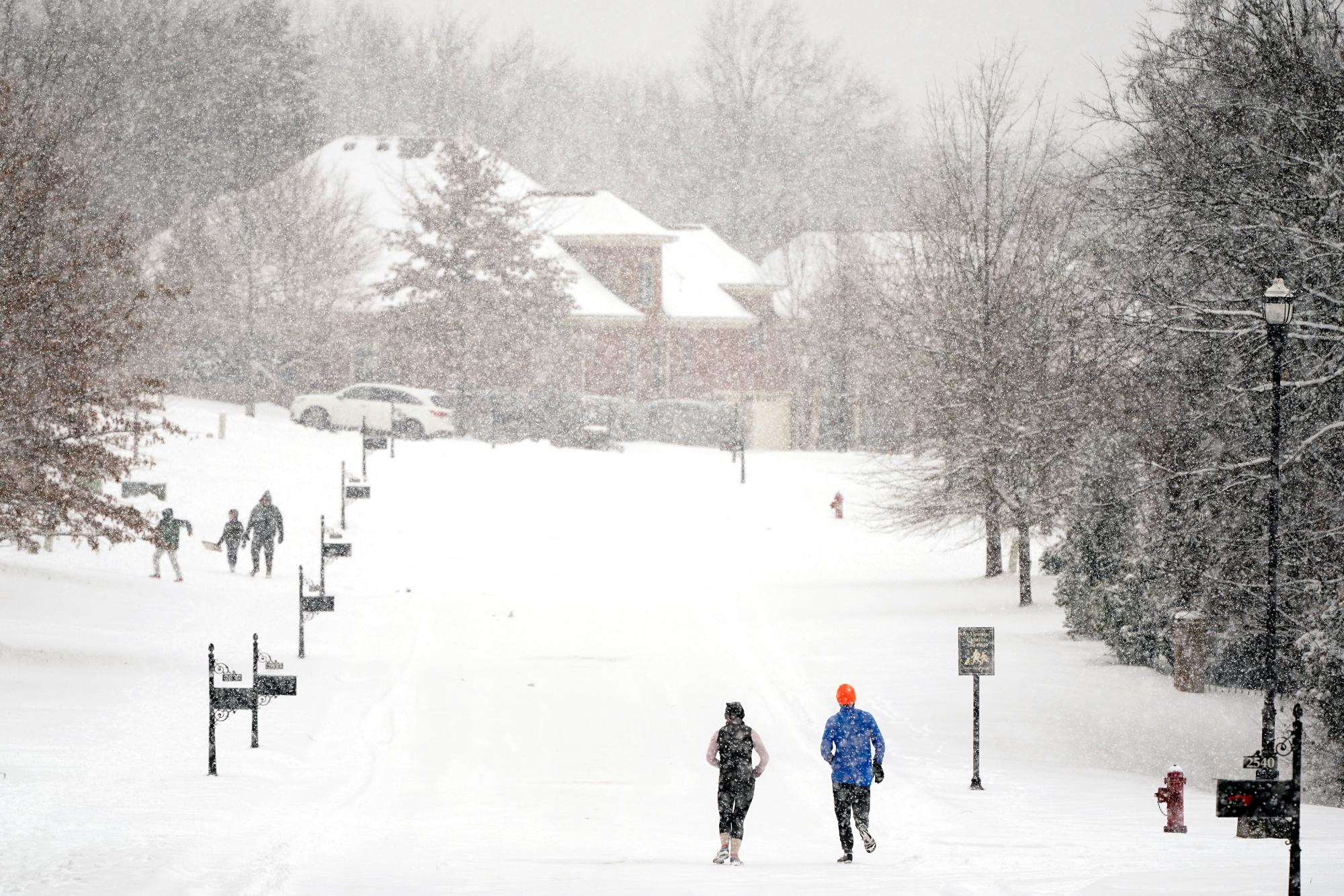 Los corredores corren por una calle sin automóviles el jueves 18 de febrero de 2021 en Nolensville, Tennessee. Una segunda tormenta de invierno en una semana está trayendo más nieve a gran parte de Tennessee. (AP Photo/Mark Humphrey)