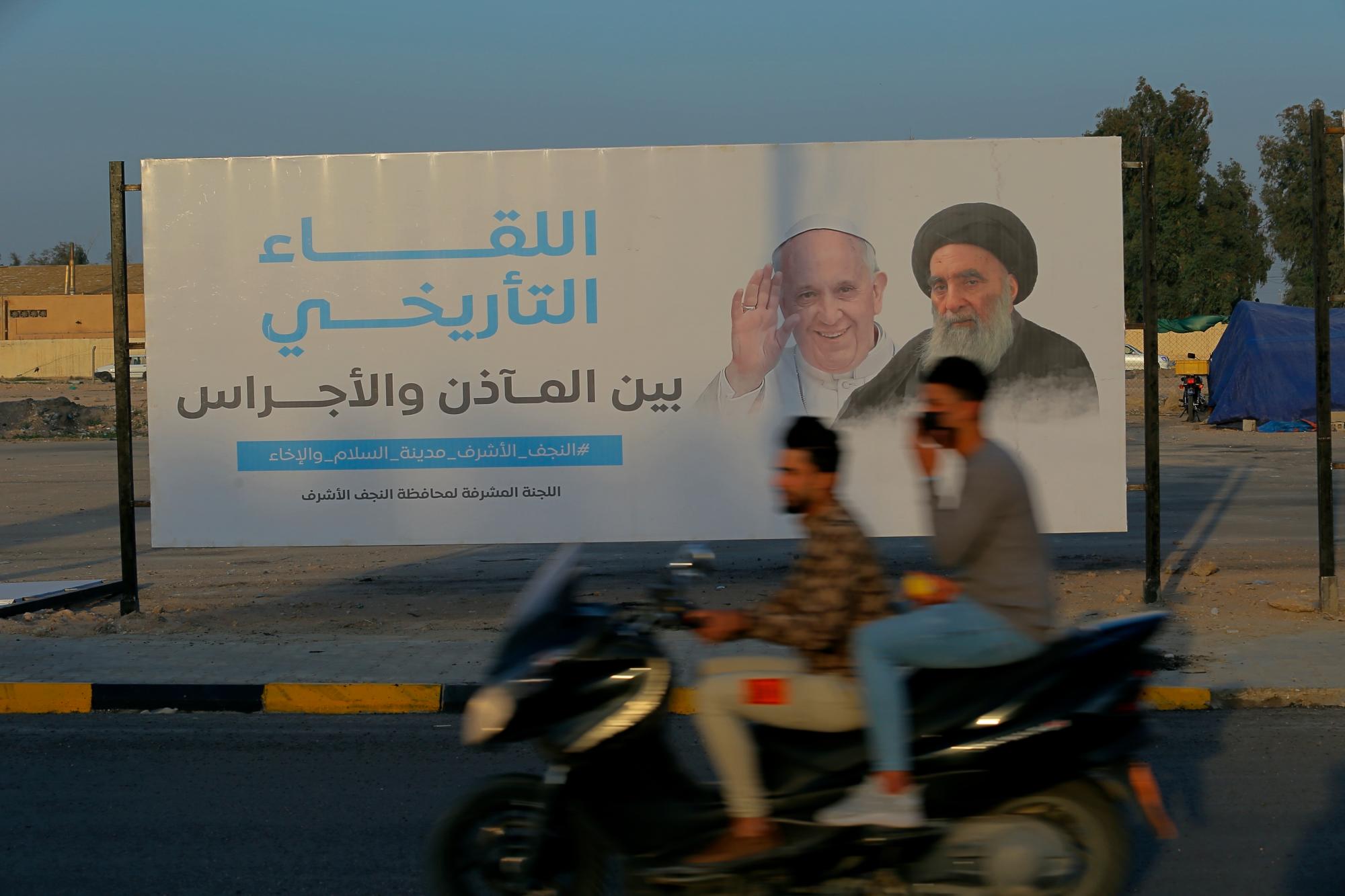 Los iraquíes colocaron un cartel anunciando la próxima visita del Papa Francisco y una reunión con un venerado líder musulmán chiíta, el Gran Ayatolá Ali al-Sistani, a la derecha, en Najaf, Irak, el jueves 4 de marzo de 2021. (AP Photo/Anmar Khalil)